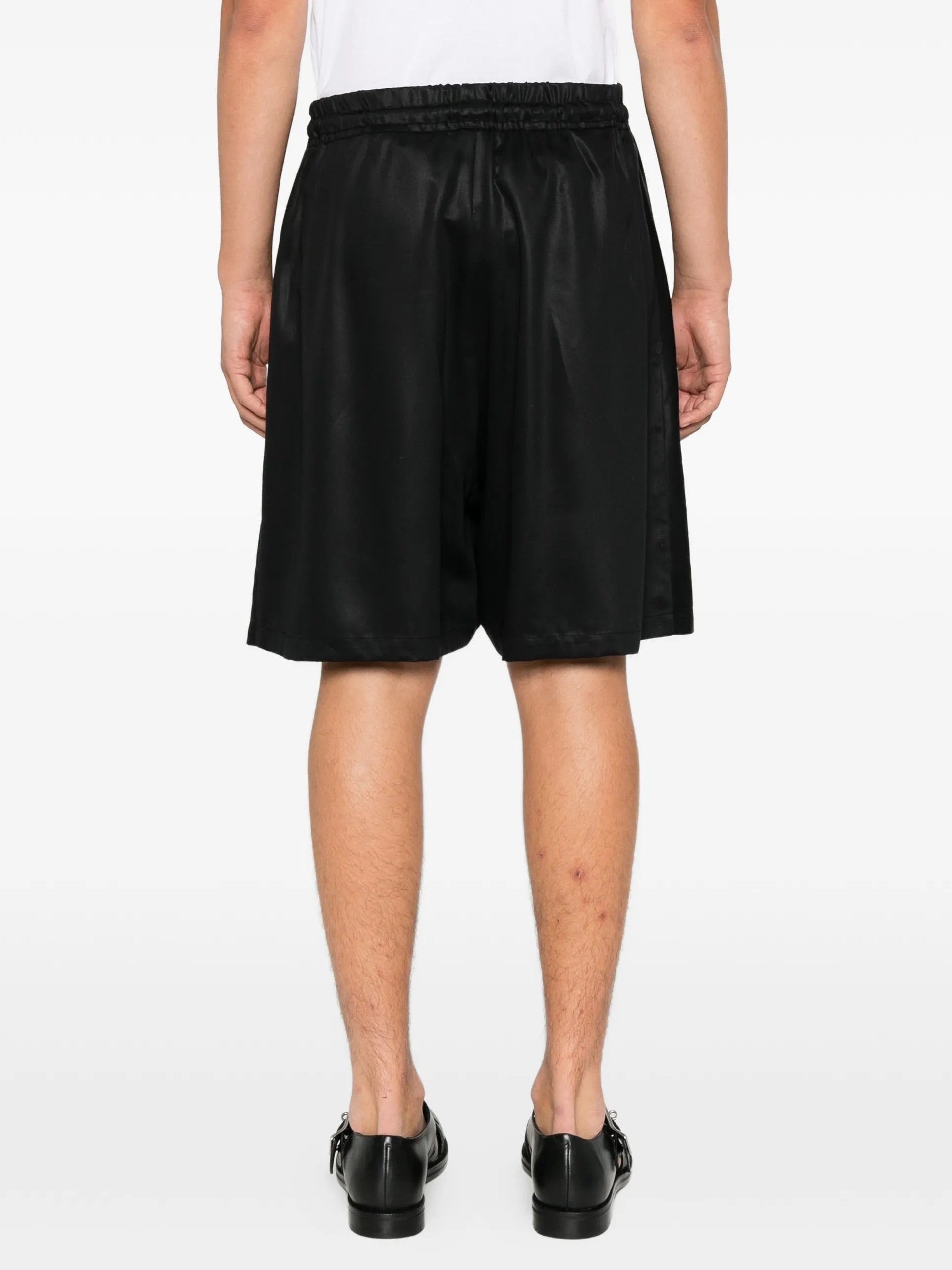 House Of The Very Islands Asher Pants in Black - three-quarter view on model showing elasticated waist and satin finish