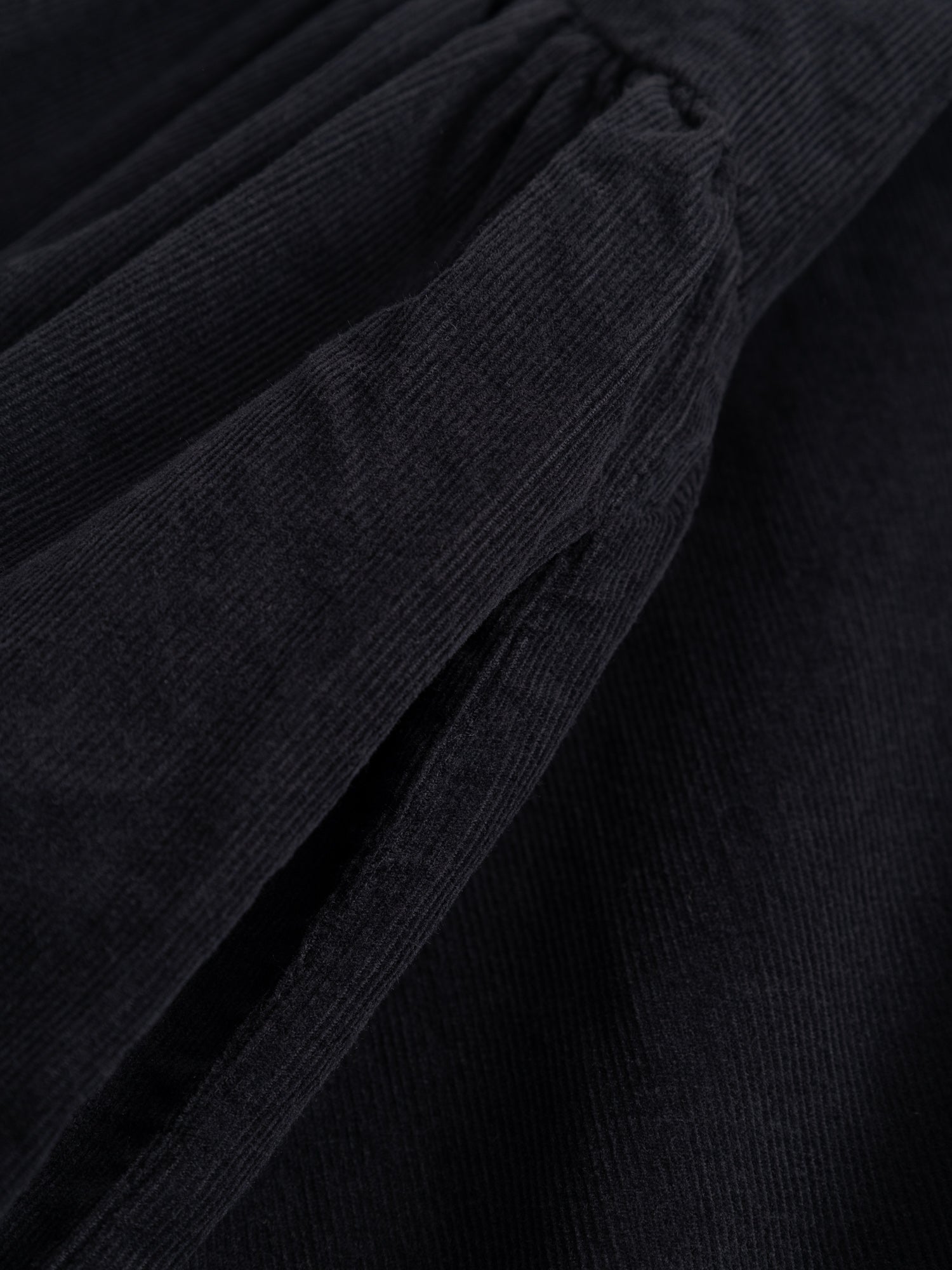 Alternate detail close-up of the Black Crane Tradi Dress focusing on the long sleeve finish and structured corduroy fabric.
