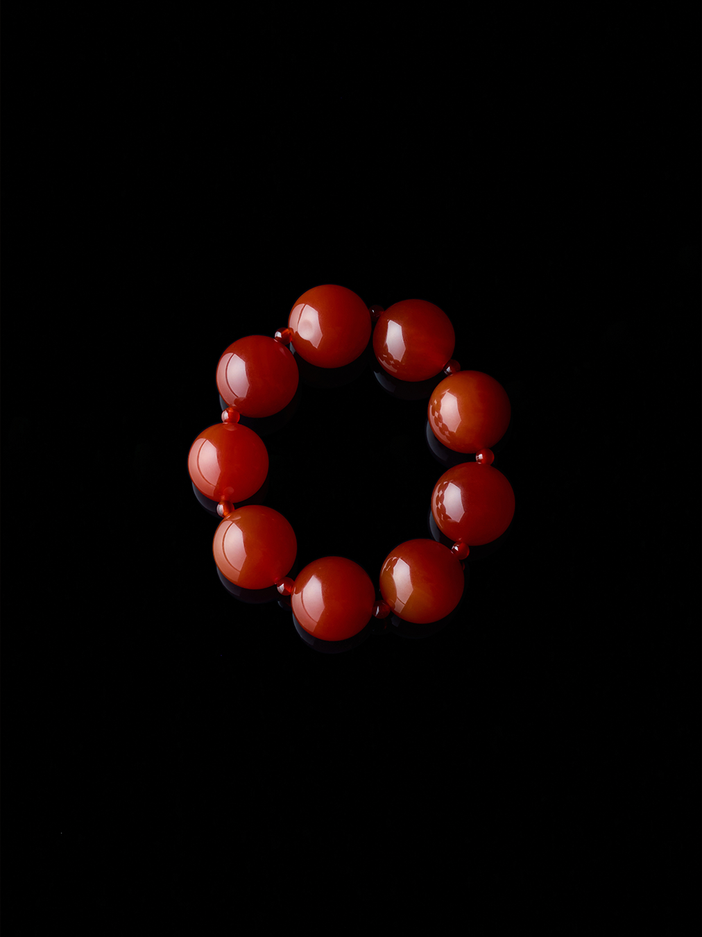 Round, natural red agate bracelet from De Silang on a black background