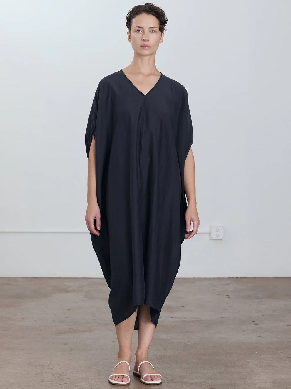Black Crane Draped Dress in Faded Black - three-quarter view on model showing dolman sleeve and draped silhouette