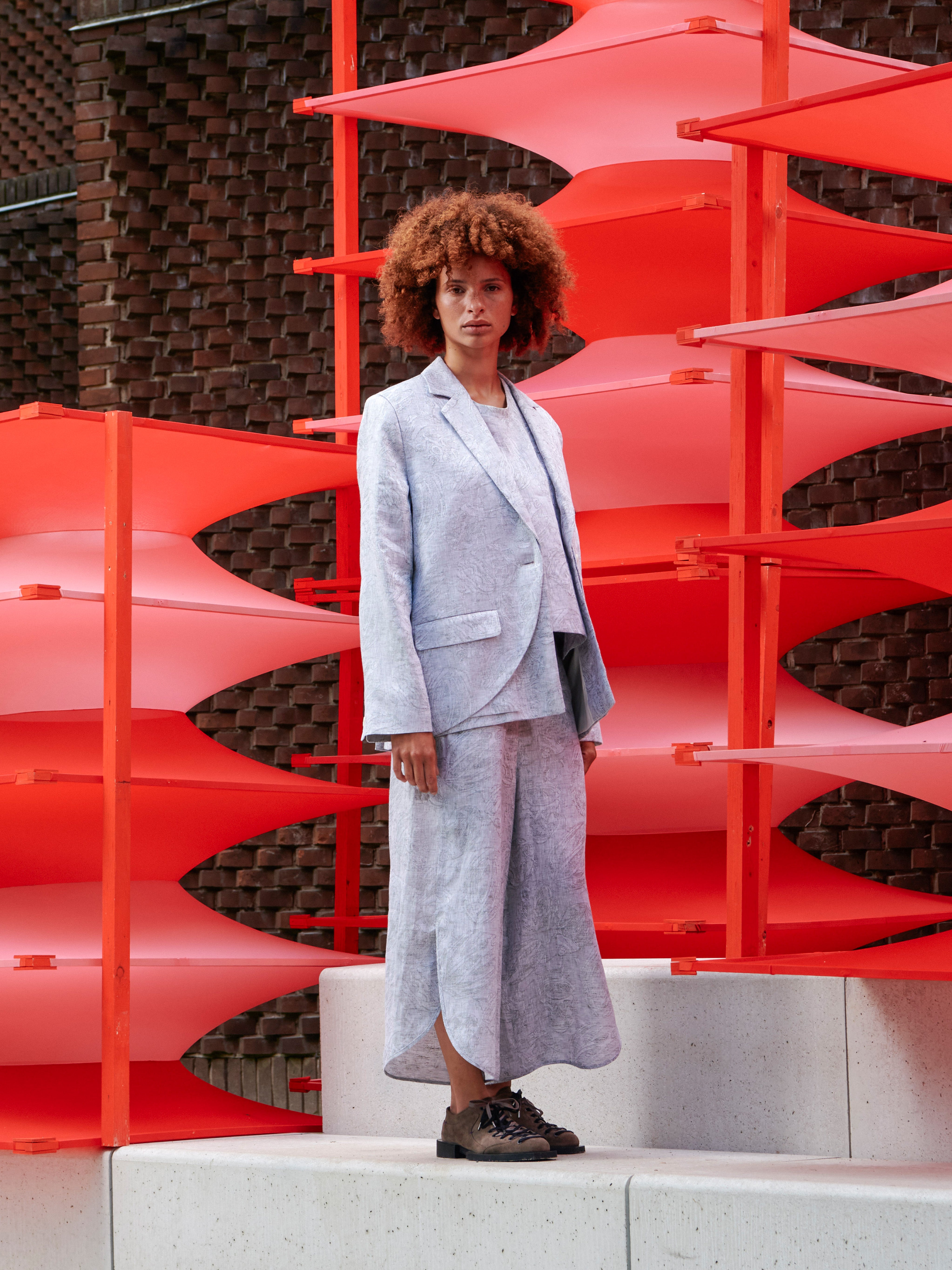 Side view of a model wearing the blazer, highlighting the layered design and relaxed tailoring.