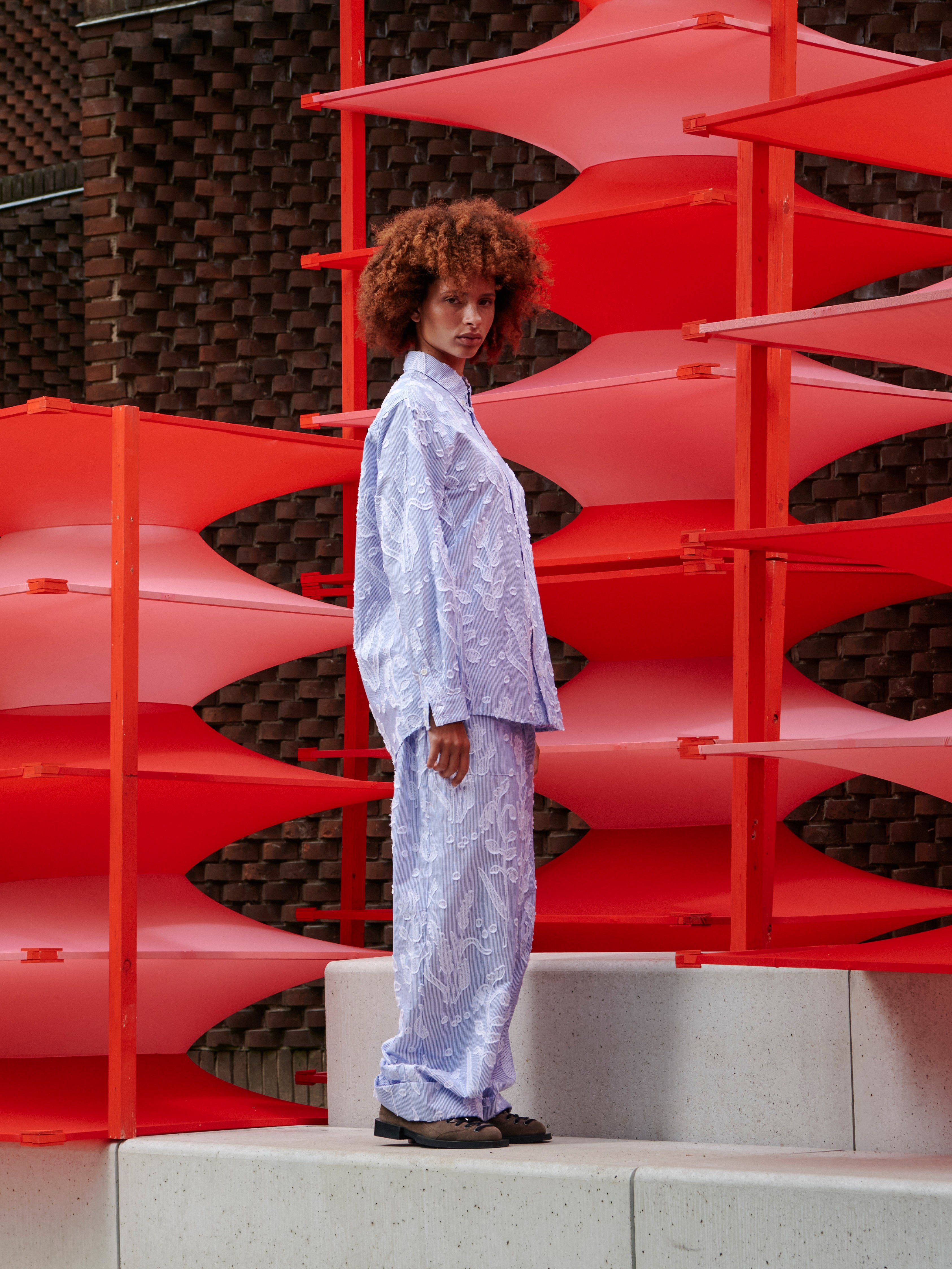 Model wearing the Block Shirt in Crops white and blue striped long sleeve shirt with curved hem, side view – Henrik Vibskov Spring/Summer 2026 Key Collection
