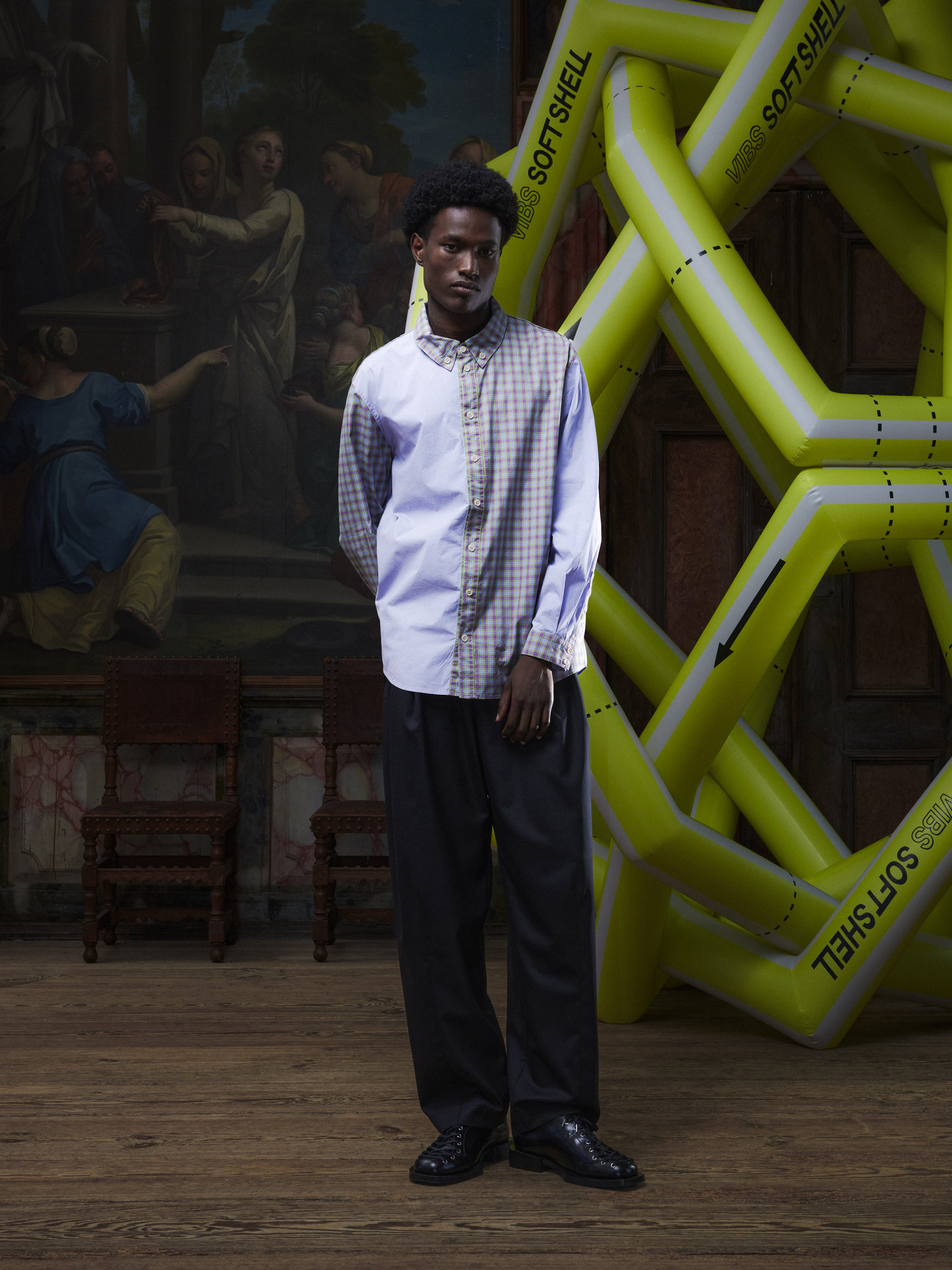 Front view of the male model wearing the Block Shirt in lilac from Henrik Vibskov Spring/Summer 2026 Studio Collection, displaying the half-lilac, half-checked pattern, classic collar, and buttoned front.