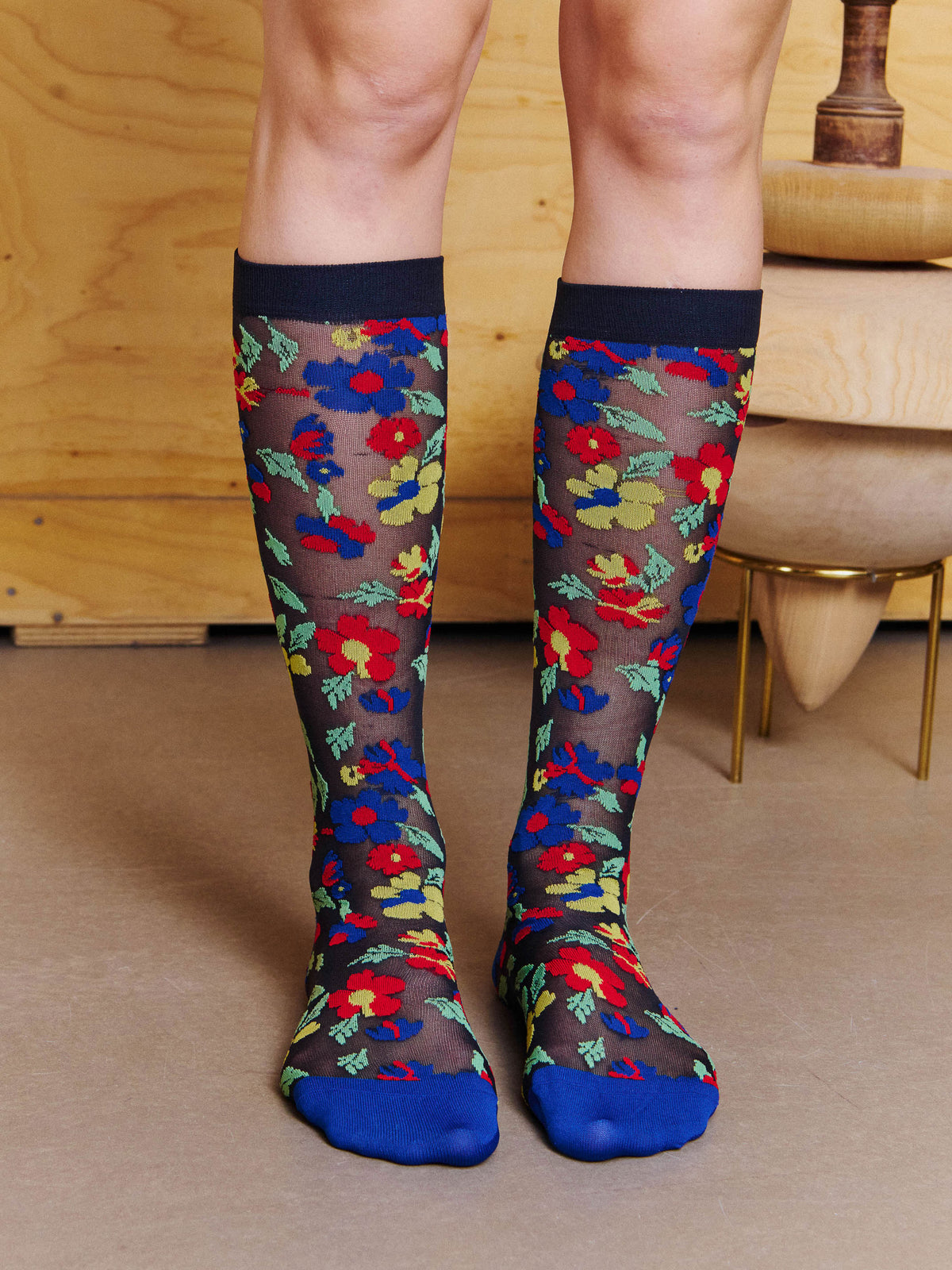 Angled view of model wearing the Henrik Vibskov Bouquet Socks in Blue Floral Affairs, showing the floral motif, semi-sheer knit and contrast toe.