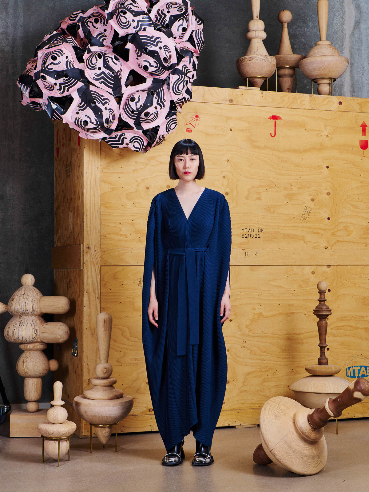Model wearing Henrik Vibskov Cherry Plisse Kaftan in Dress Blues from the front, showing the long cocoon silhouette, V-neck and waist tie.