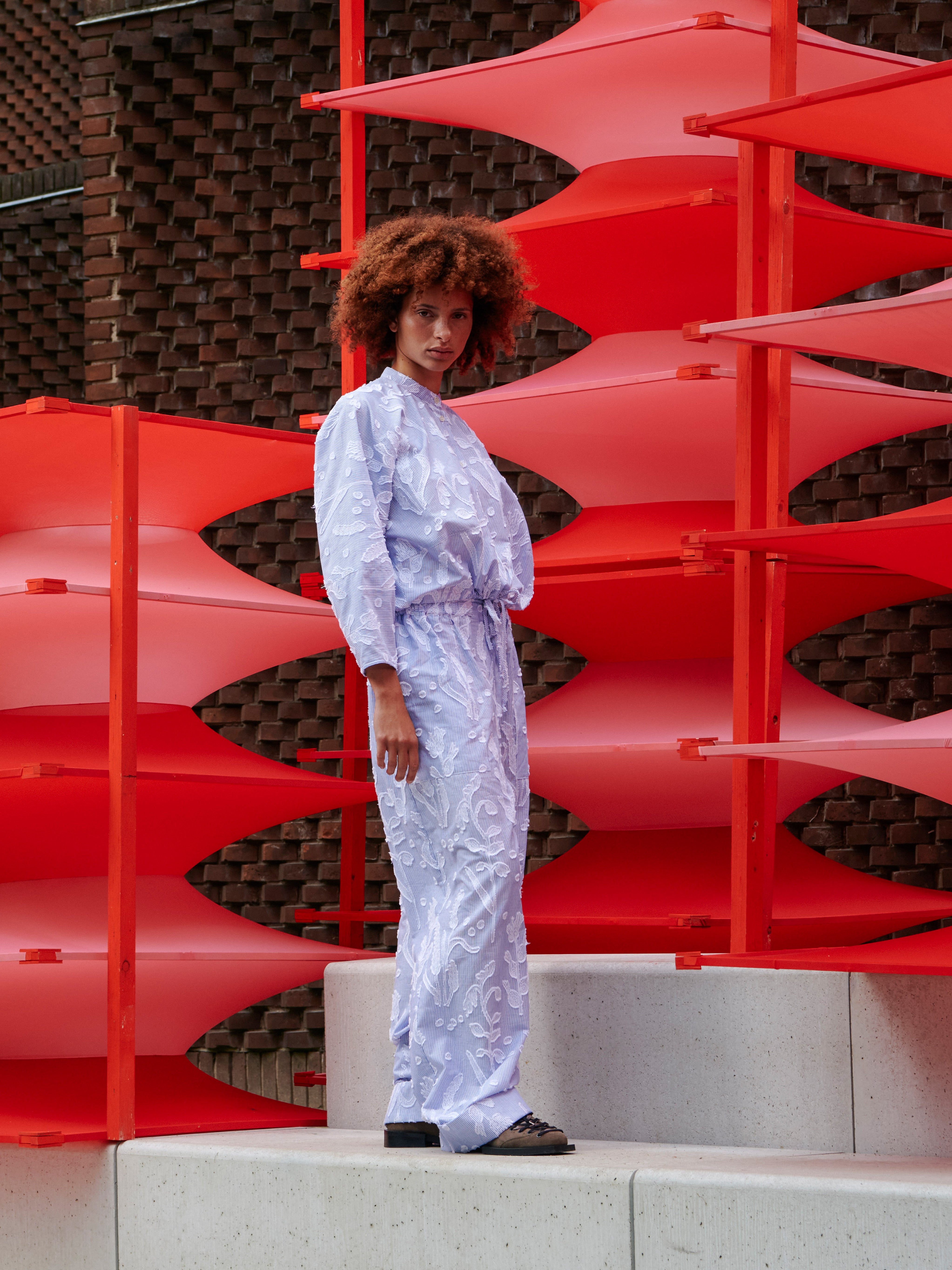 Side view of a model wearing the Flat Shirt, emphasizing the relaxed, slightly cropped shape with elastic hem.