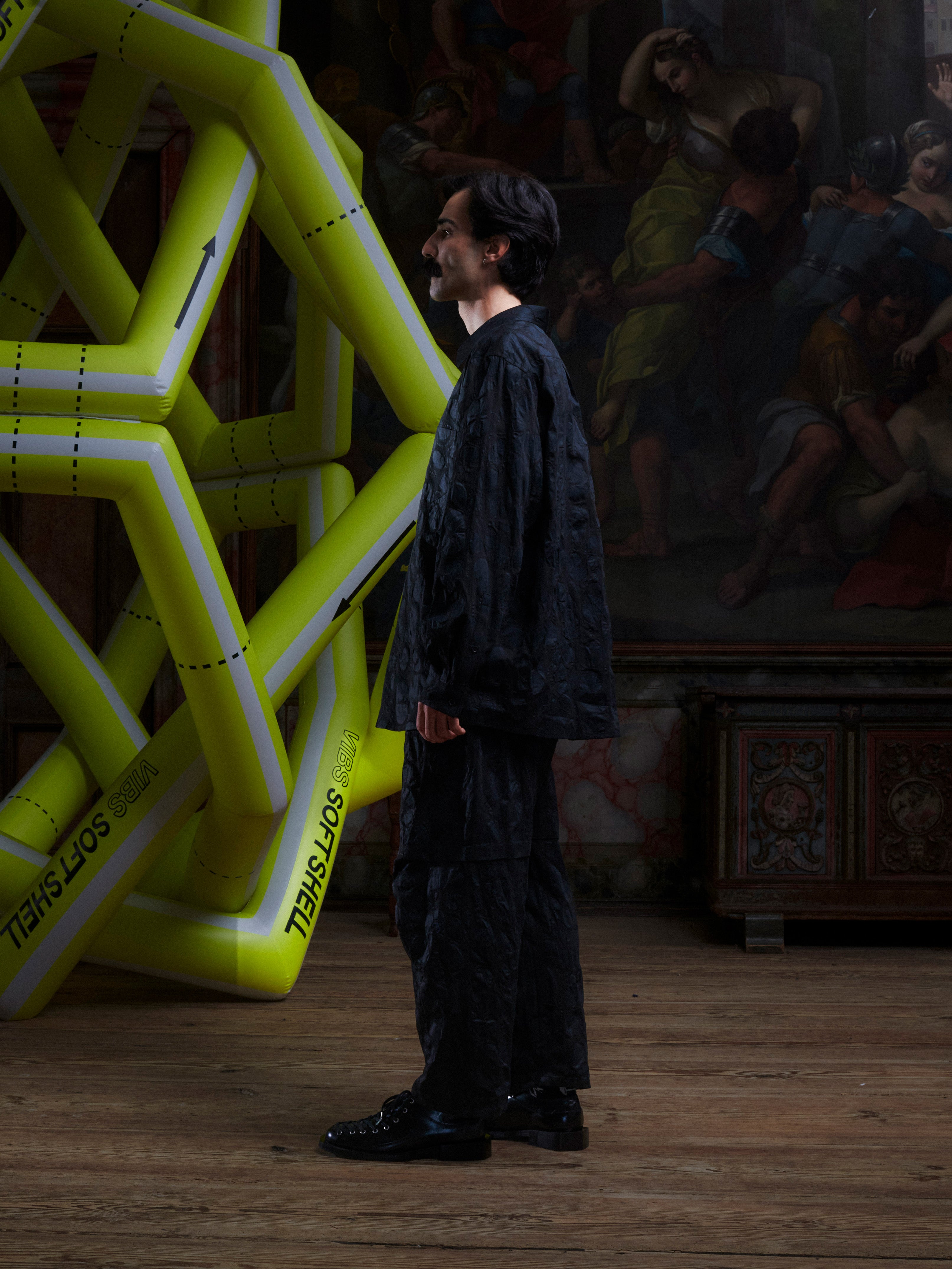 Model wearing the Henrik Vibskov New Blou Shirt in Black Amulets, side view, showing the long sleeves, straight hem, and tonal amulets pattern.