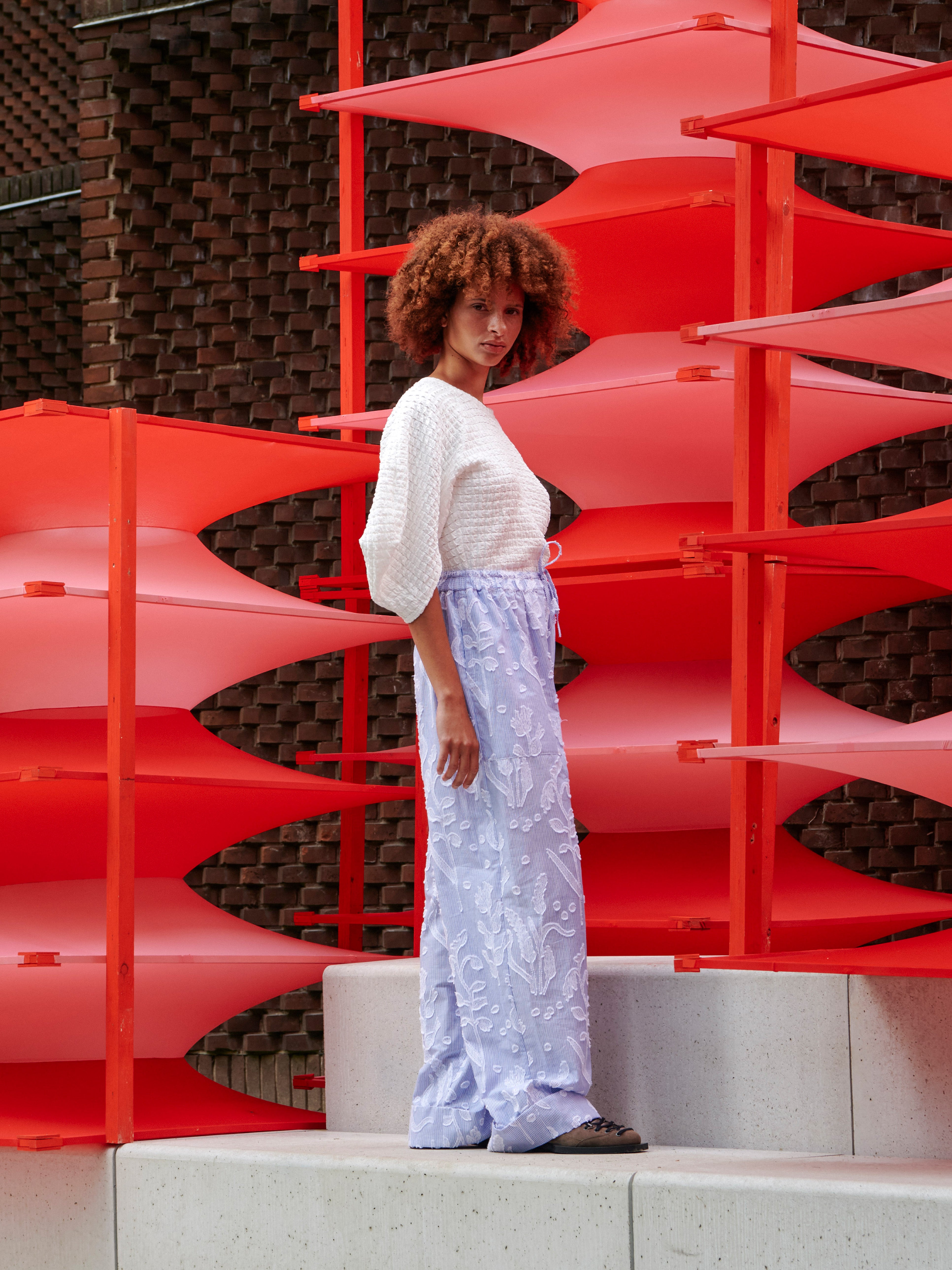 Side view of model wearing the Persey Top, emphasizing the rounded 3/4 sleeves and textured fabric.