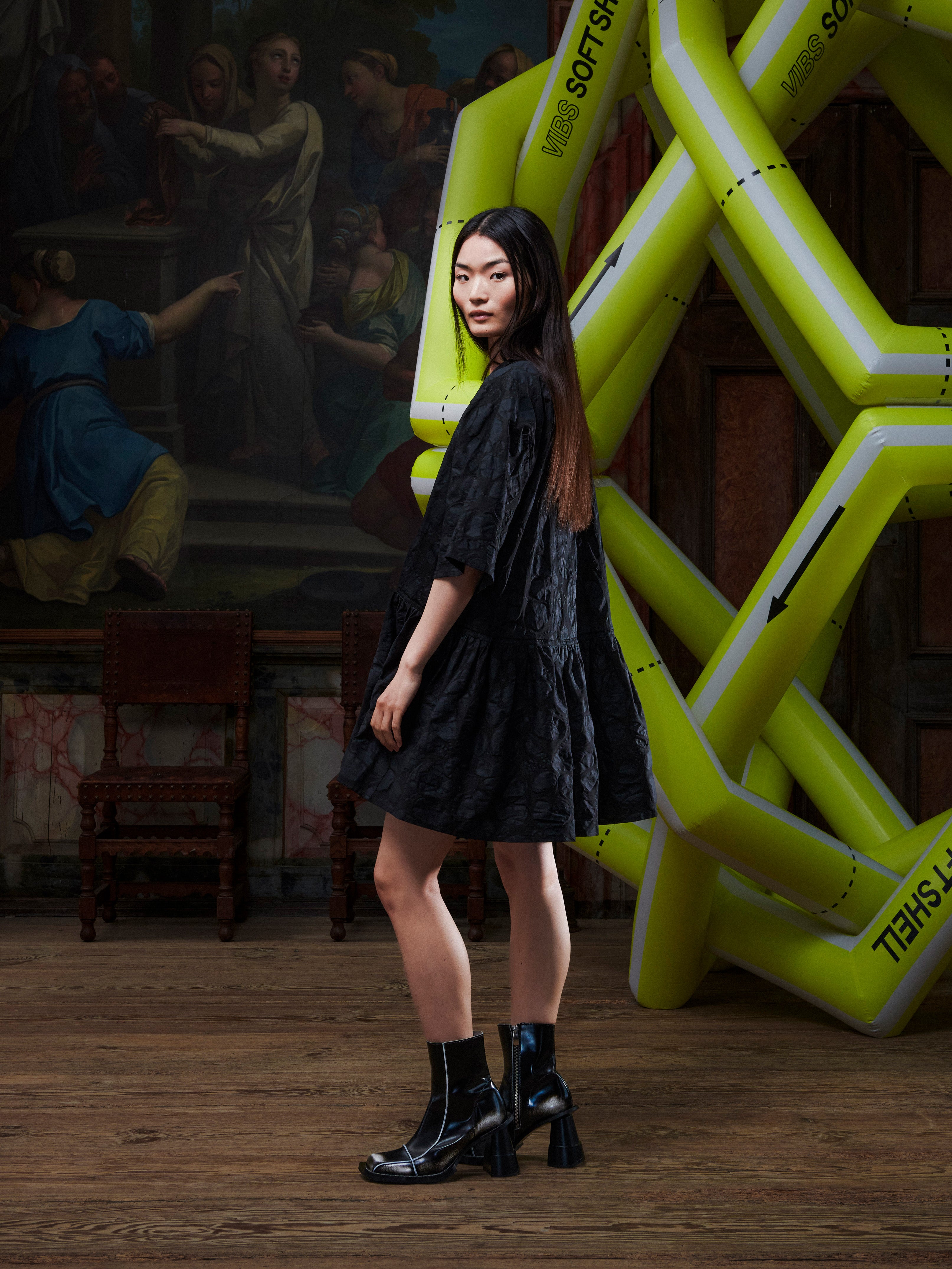Model wearing the Henrik Vibskov Preserve Blouse in Black Amulets, side view, showing the volume of the oversized silhouette, short sleeves, and wide, knee-length skirt.