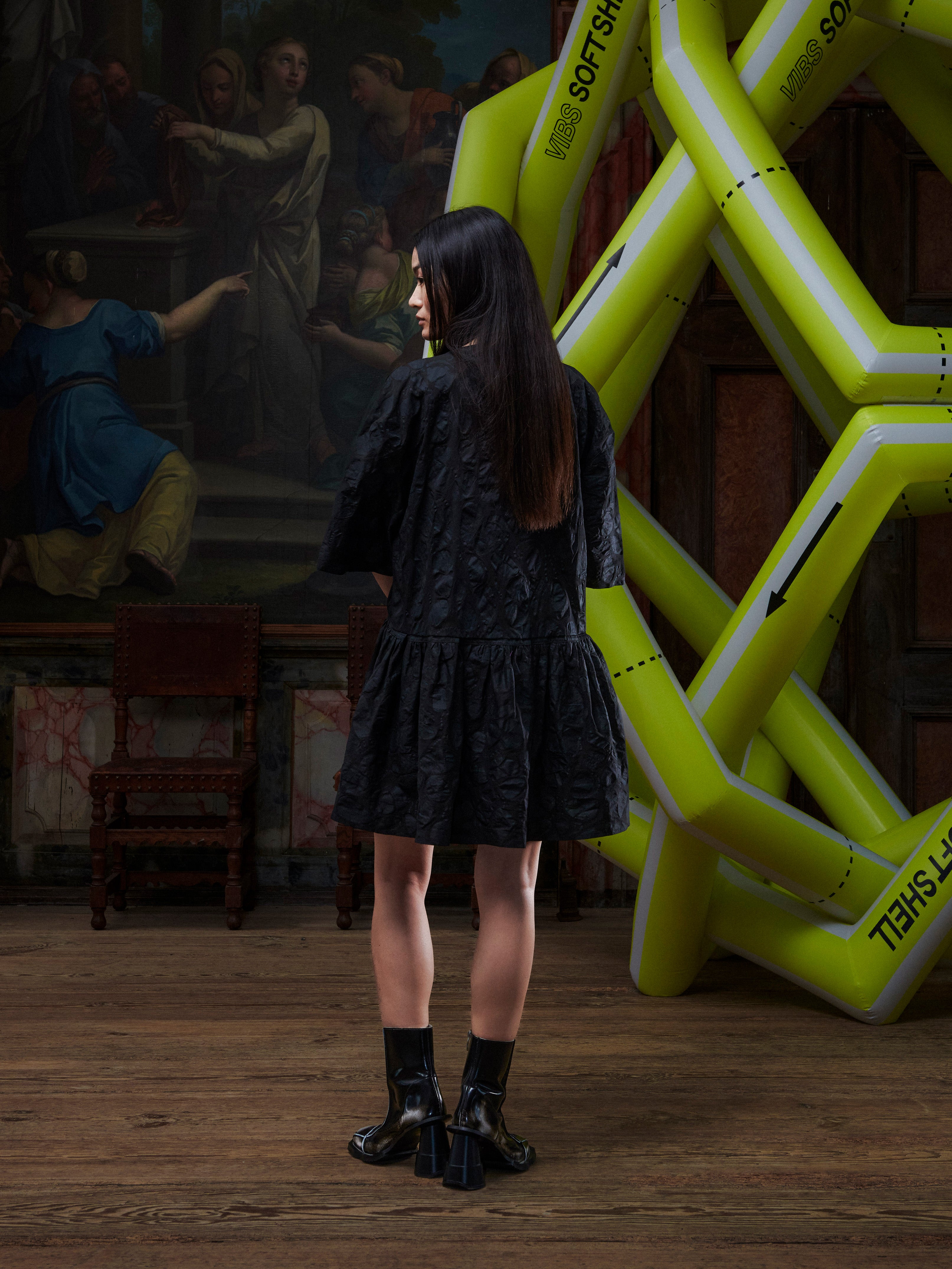 Model wearing the Henrik Vibskov Preserve Blouse in Black Amulets, back view, showing the full amulet pattern, oversized shape, and wide, knee-length skirt.