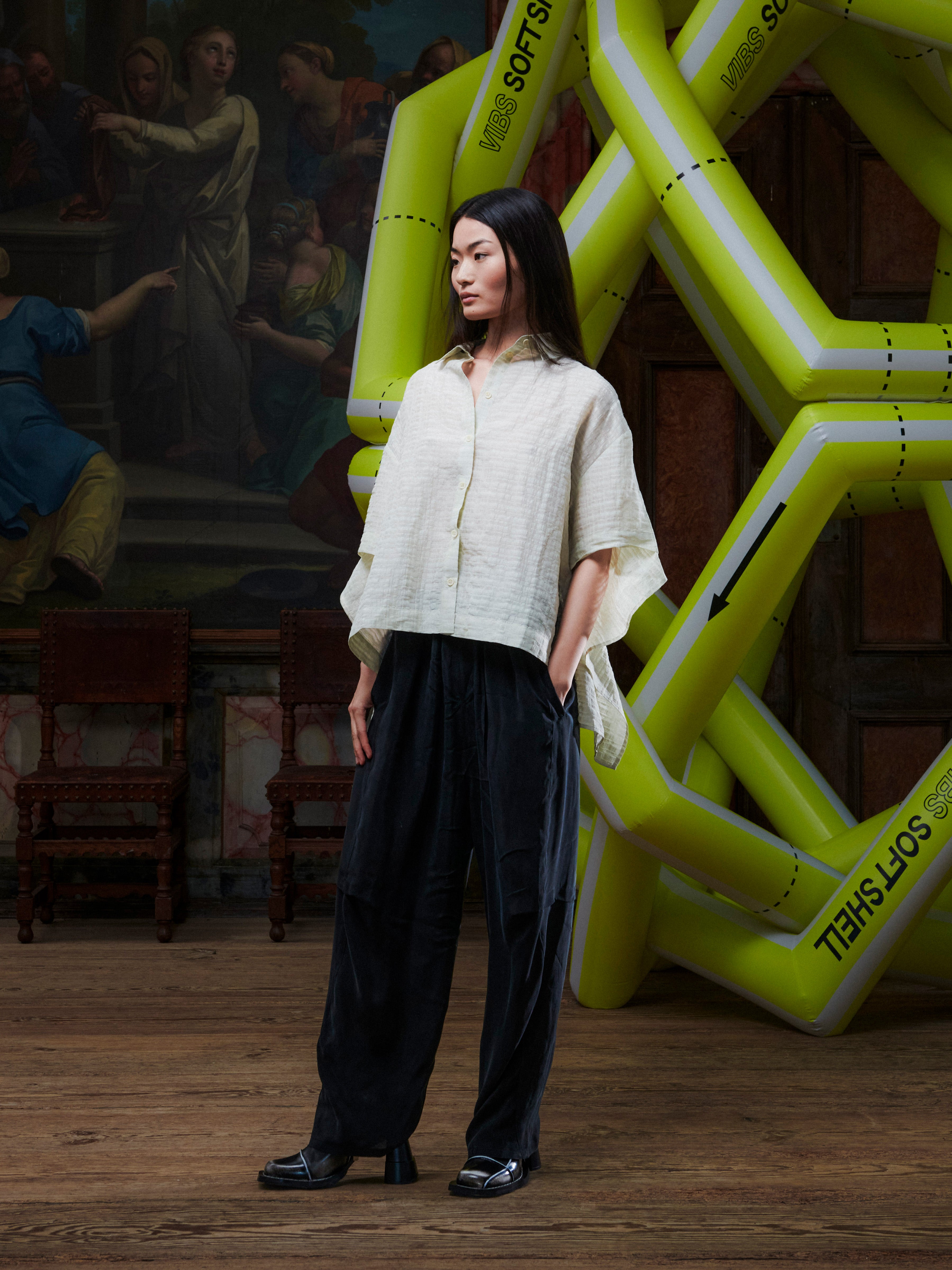 Person wearing a white top and black pants standing in front of a large inflatable sculpture with text.