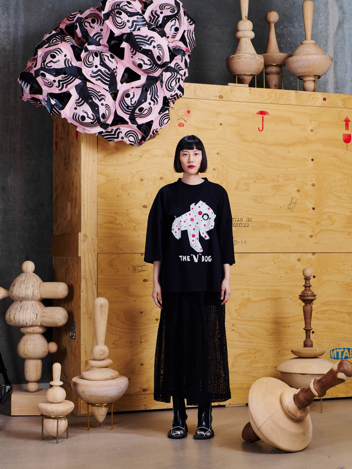 Model wearing the Henrik Vibskov V Dog Tee in Black styled with a long black skirt, showing the oversized silhouette and front graphic.
