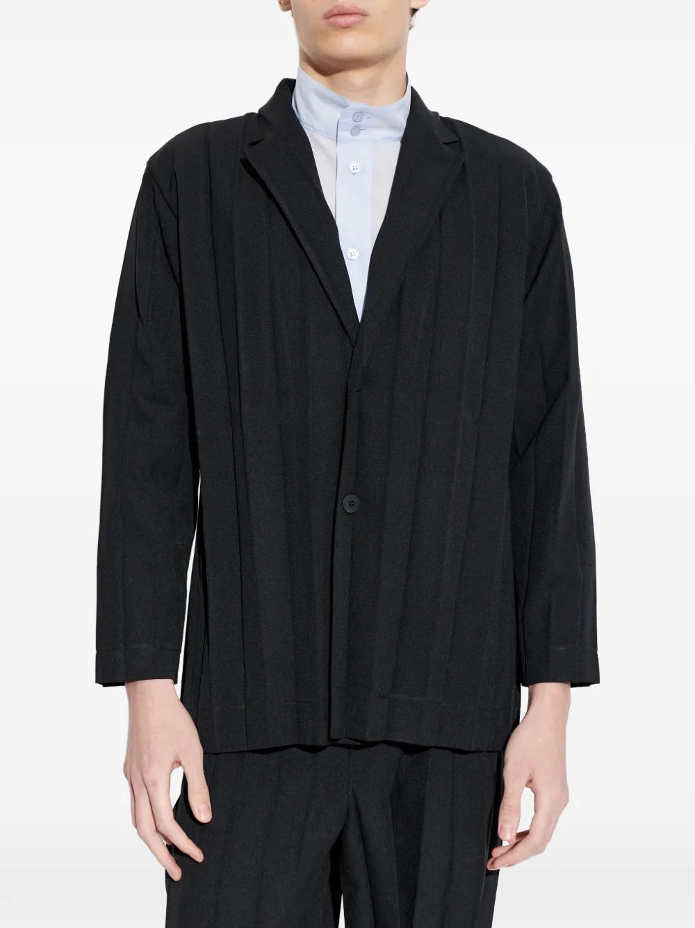 Model wearing Edge Ensemble Jacket in Black by Homme Plissé Issey Miyake, front closeup of notched collar and two-button closure on black large plissé blazer