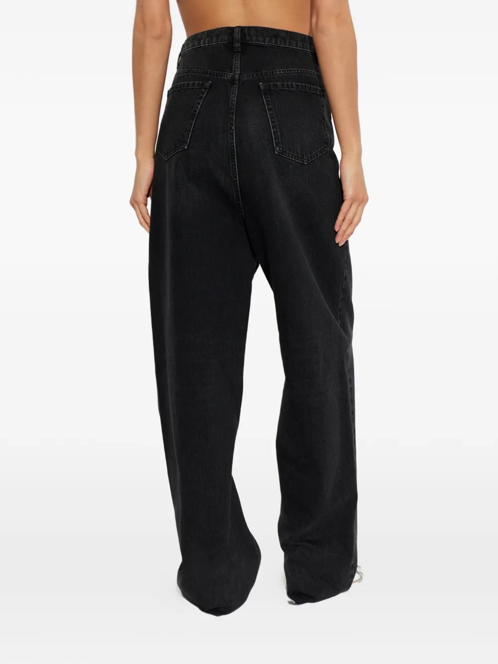 Model wearing Pants 5 Pockets in Medium Black by Maison Margiela, back view of high-waist straight-leg faded black denim jeans with raw-cut hem and five-pocket design, Spring/Summer 2026