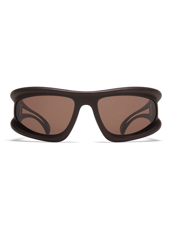Mykita x 032c MARFA Sunglasses in ebony and brown, front view showing oversized wraparound silhouette with chunky matte ebony frame, brown tinted lenses, and curved architectural nose bridge with sculpted cutout detailing