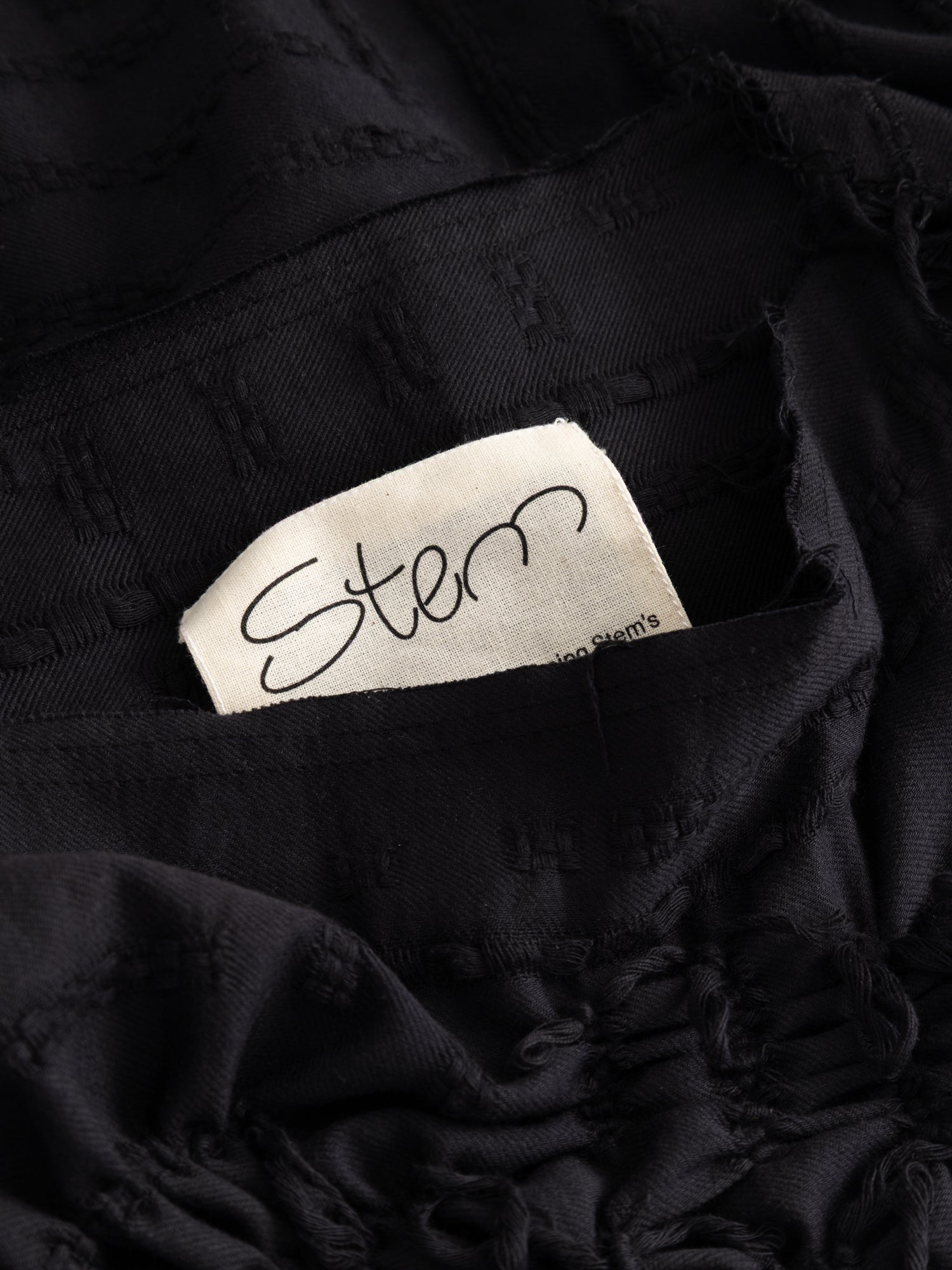 Stem Basket Tee in black, close-up of interior Stem label against woven basket-weave lining