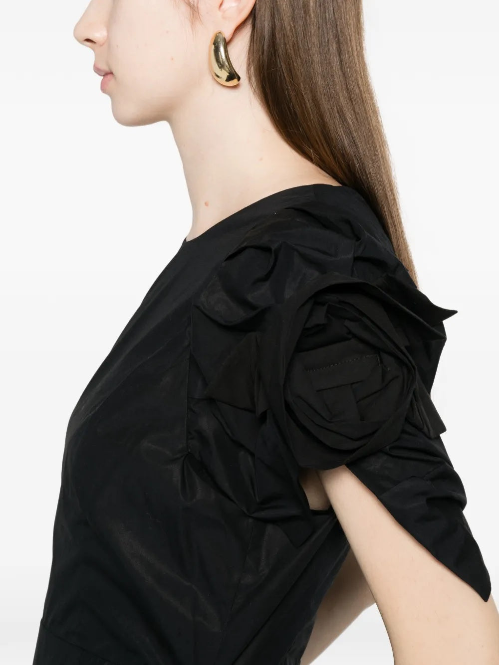 Close-up of the dress highlighting the petal-shaped puff sleeve and rosette appliqué in crisp black cotton poplin.