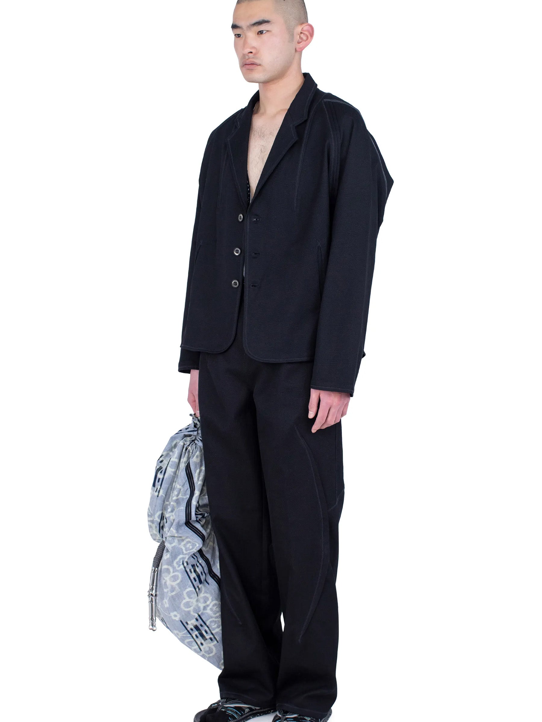 Side view of the model wearing the Kiko Kostadinov Vig K-Dart Blazer in Space Black.