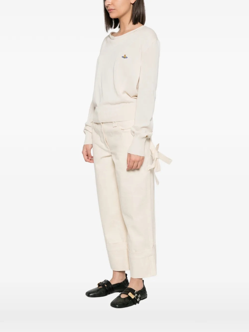 Model wearing Pamela Jumper in Cream by Vivienne Westwood, full-length side view showing relaxed silhouette and draped cowl neckline of cream cotton jumper, Spring/Summer 2026