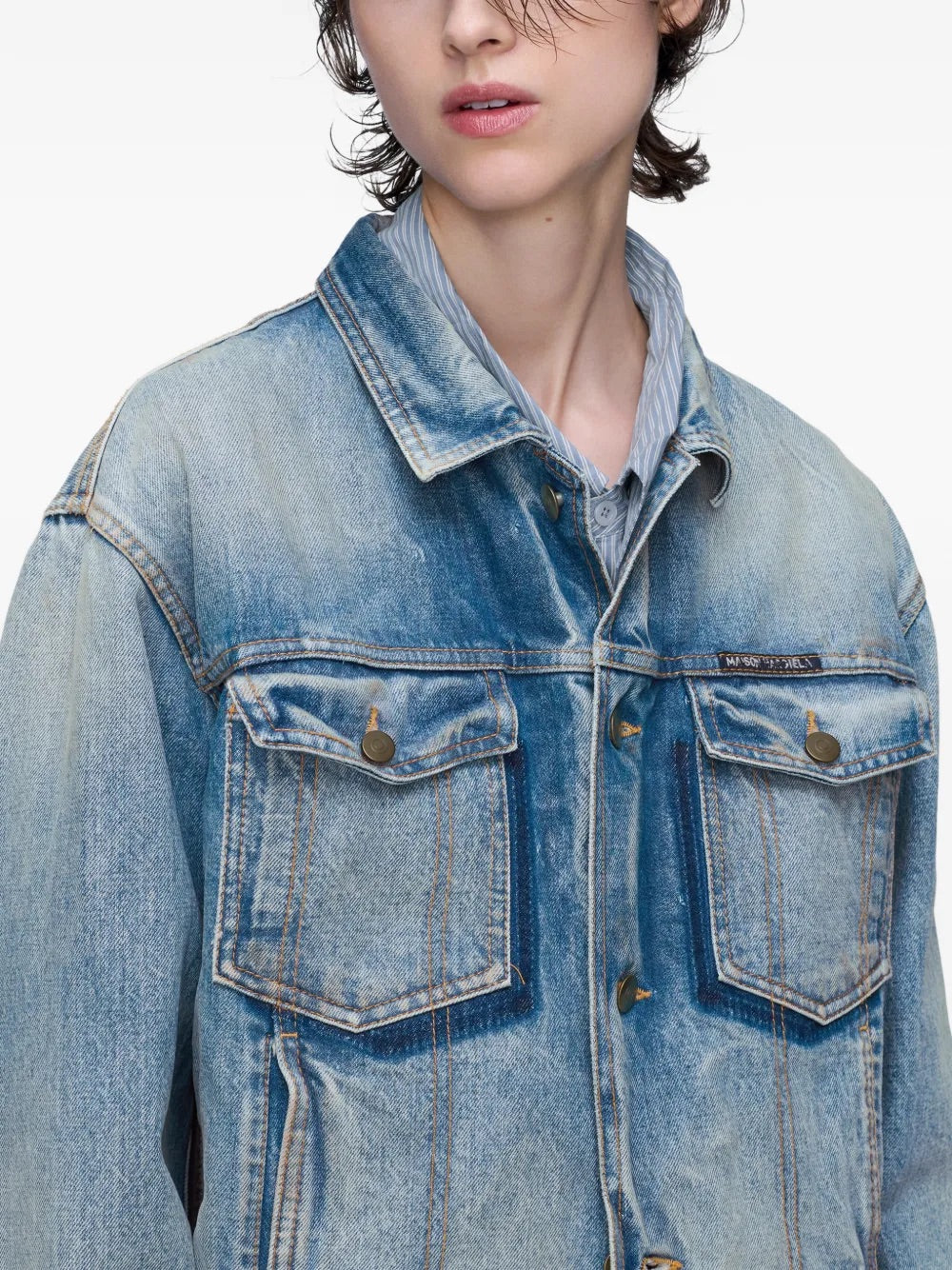 Close-up front view of a female model wearing the Maison Margiela Women’s Sports Jacket in Light Blue Indigo, focusing on the frayed detailing, button fastening, and cotton texture.