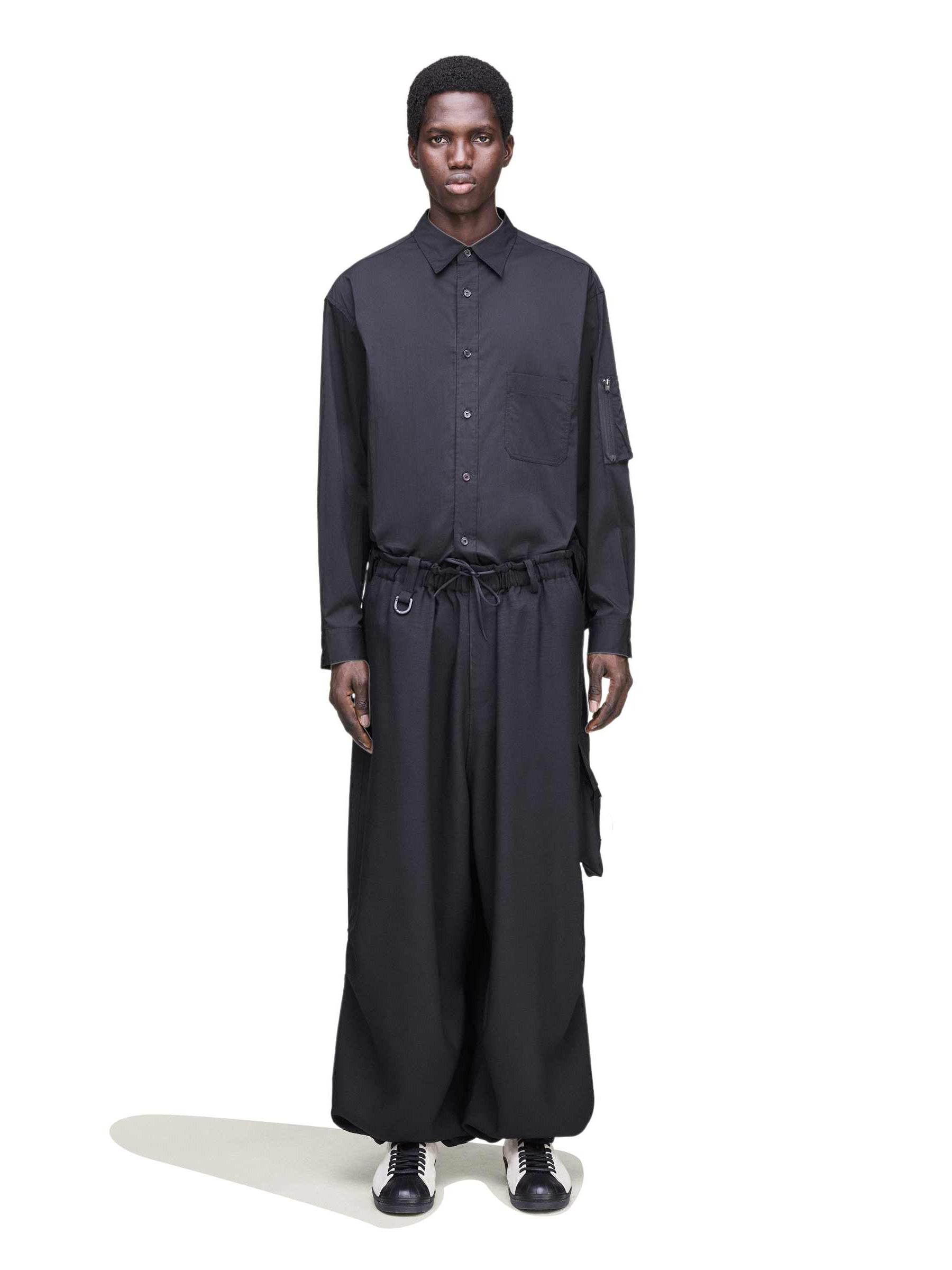 Front view of a male model wearing the Y-3 Sport Uniform Wide Cargo Trousers in Black, showing the wide-leg silhouette, cargo pocket layout, and integrated belt detail.