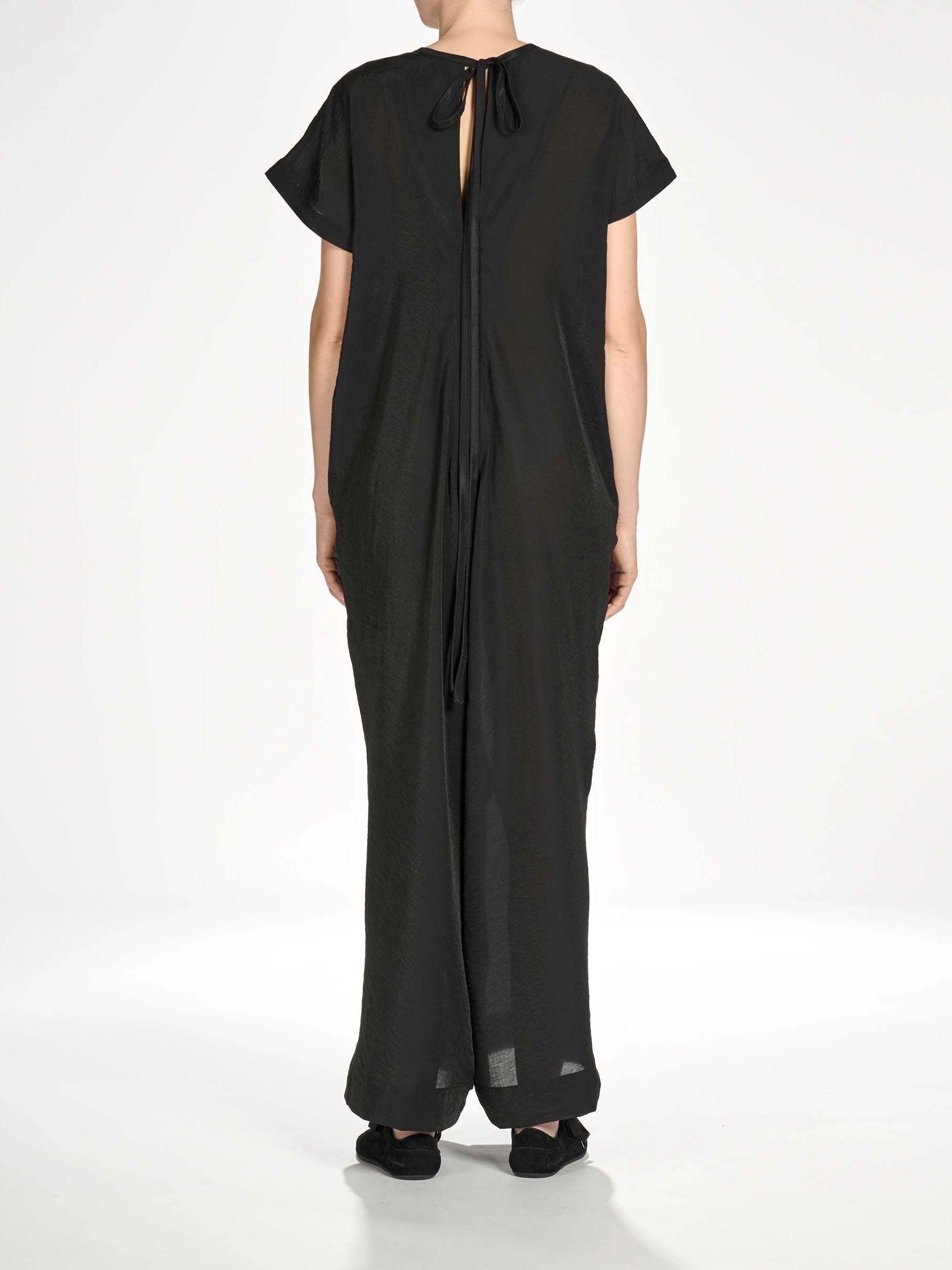 Back view of a female model wearing the Y-3 Women’s Utility Dress in Black, showing the plain weave fabric and loose silhouette.
