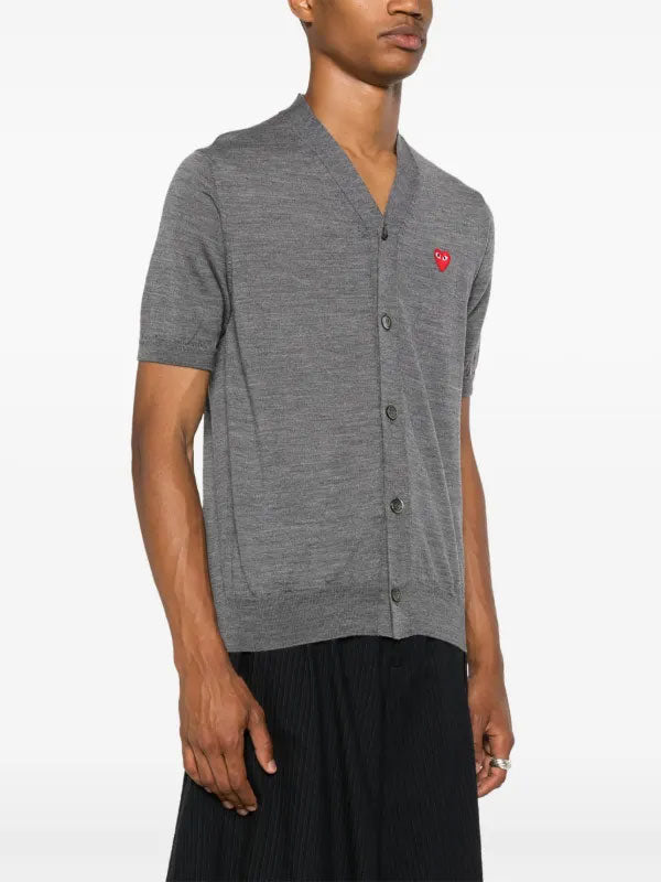 Model wearing the COMME des GARÇONS PLAY V-Neck Knit Cardigan Red Heart in Grey, showing the short-sleeve silhouette and button front.