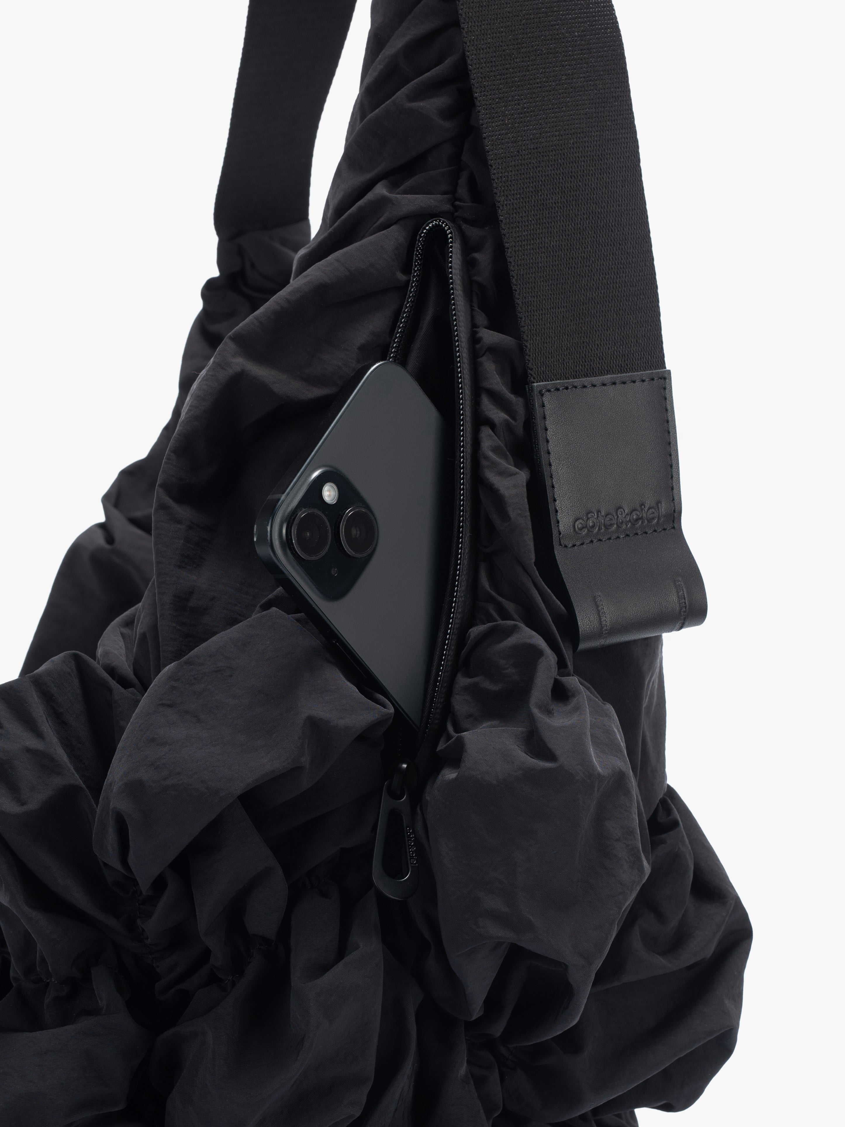Closeup of Côte&Ciel Hyco S Otra Gathered crossbody bag in black, showing external front pocket with quick-access functionality.