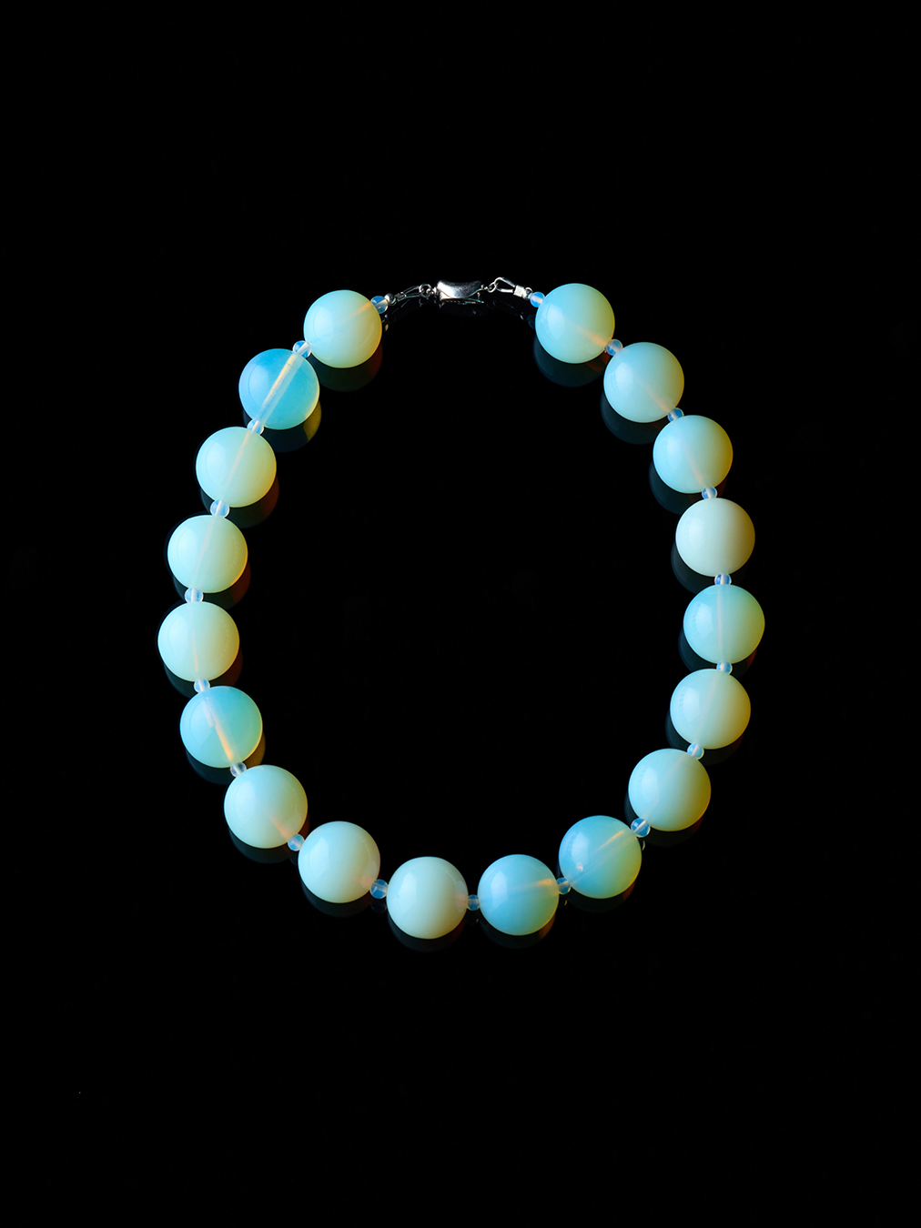 Round, opal moon necklace with silver clasp from De Silang on a black background