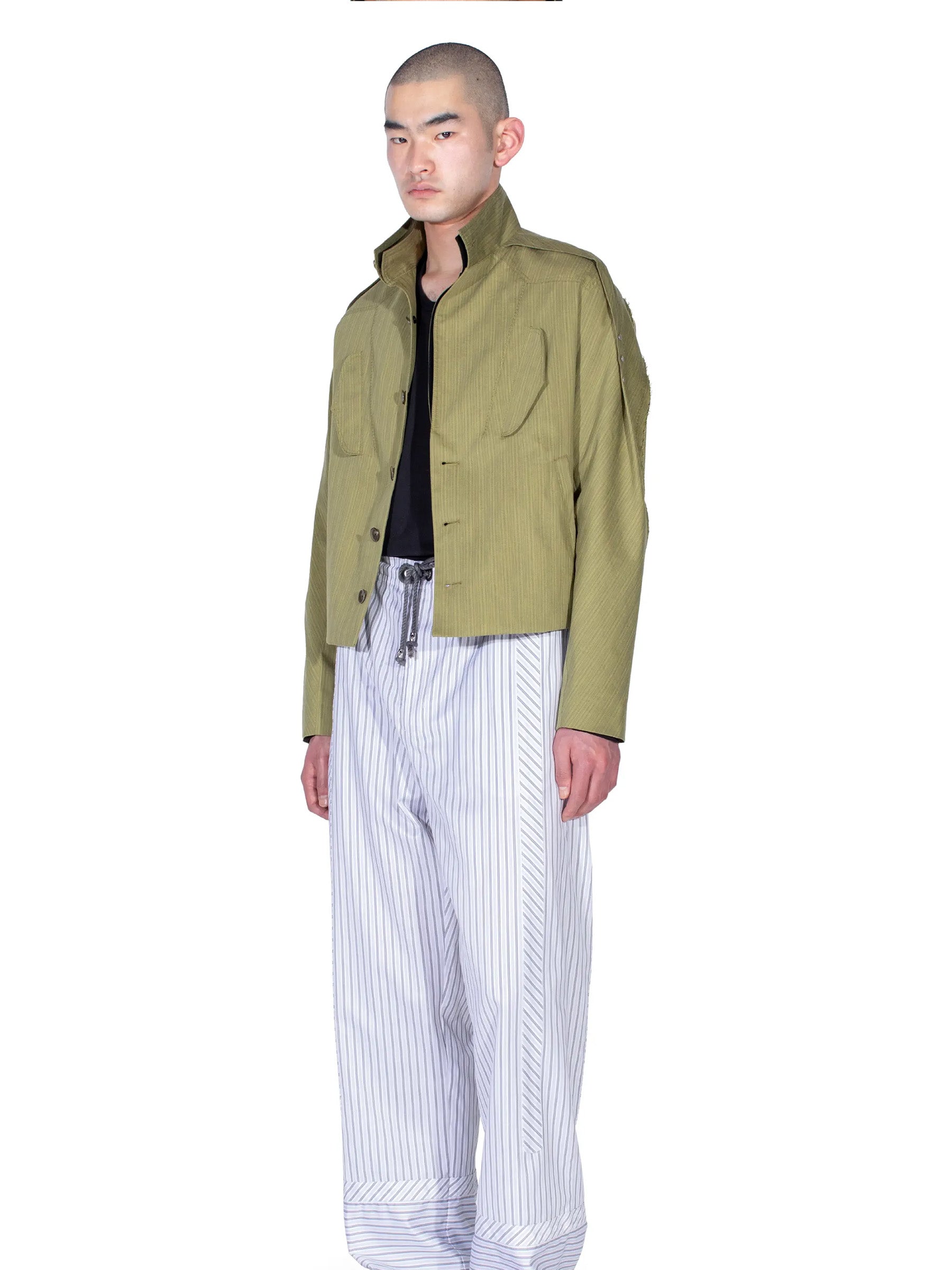  Side view of the model wearing the Kiko Kostadinov Egreta Jacket in Lime Stripe.
