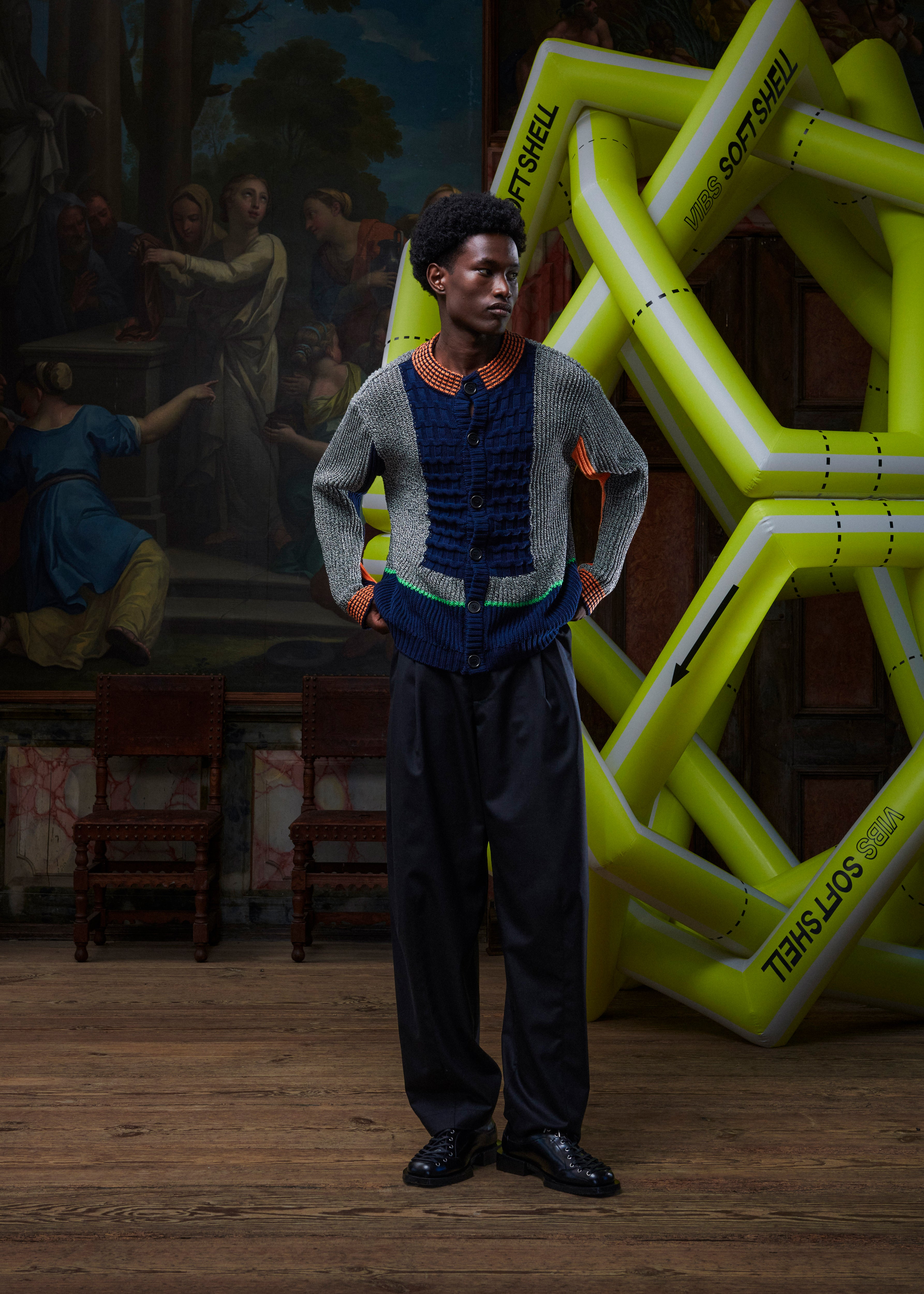 Front view of the male model wearing the Abundance Cardigan, highlighting the unisex fit, bold block-color pattern, and contrasting orange details