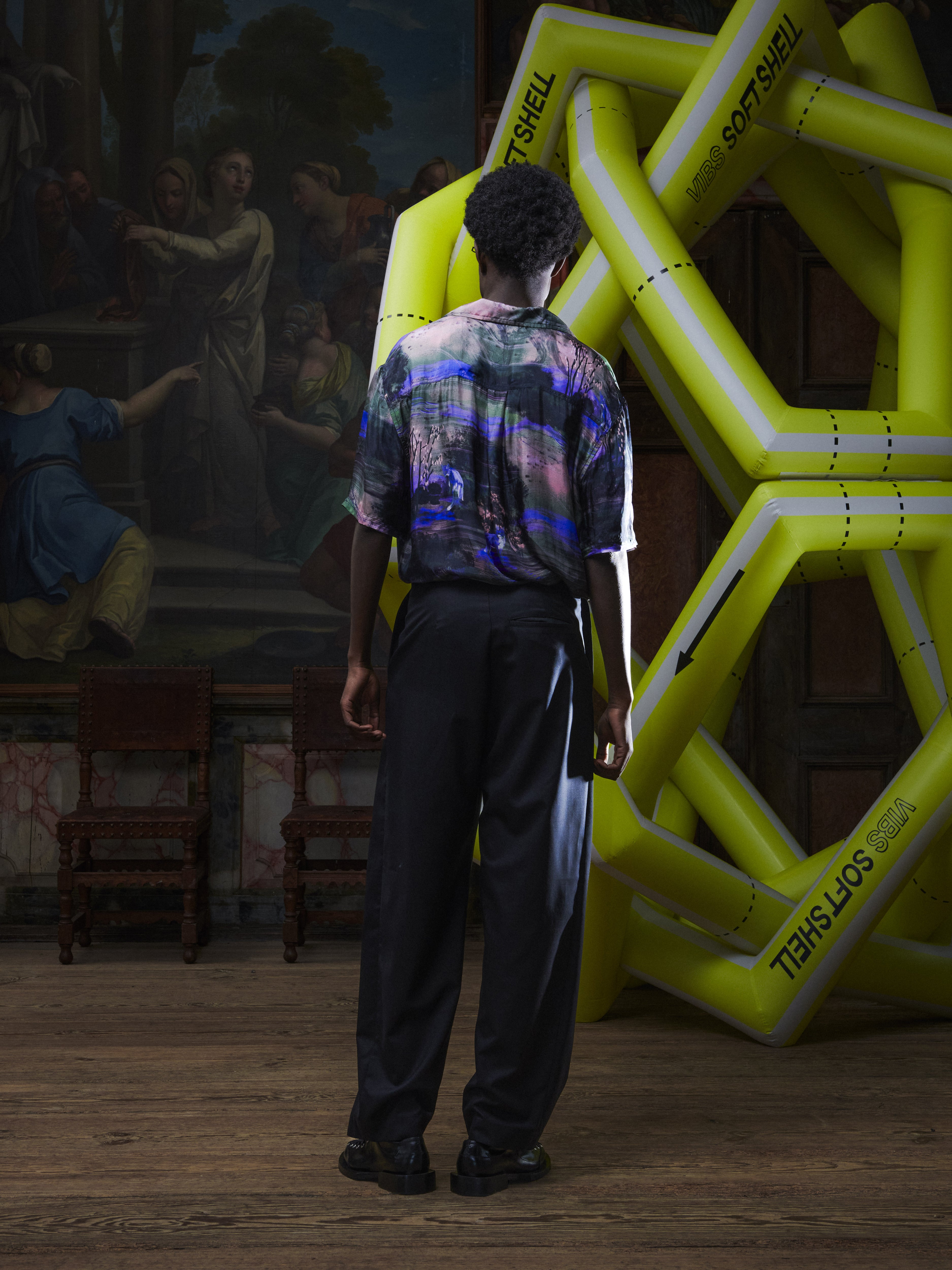 Side view of a female model wearing the Claus Pants in Tropical Black from Henrik Vibskov Spring/Summer 2026 Studio Collection, highlighting the side pockets, straight-leg profile, and unisex fit.