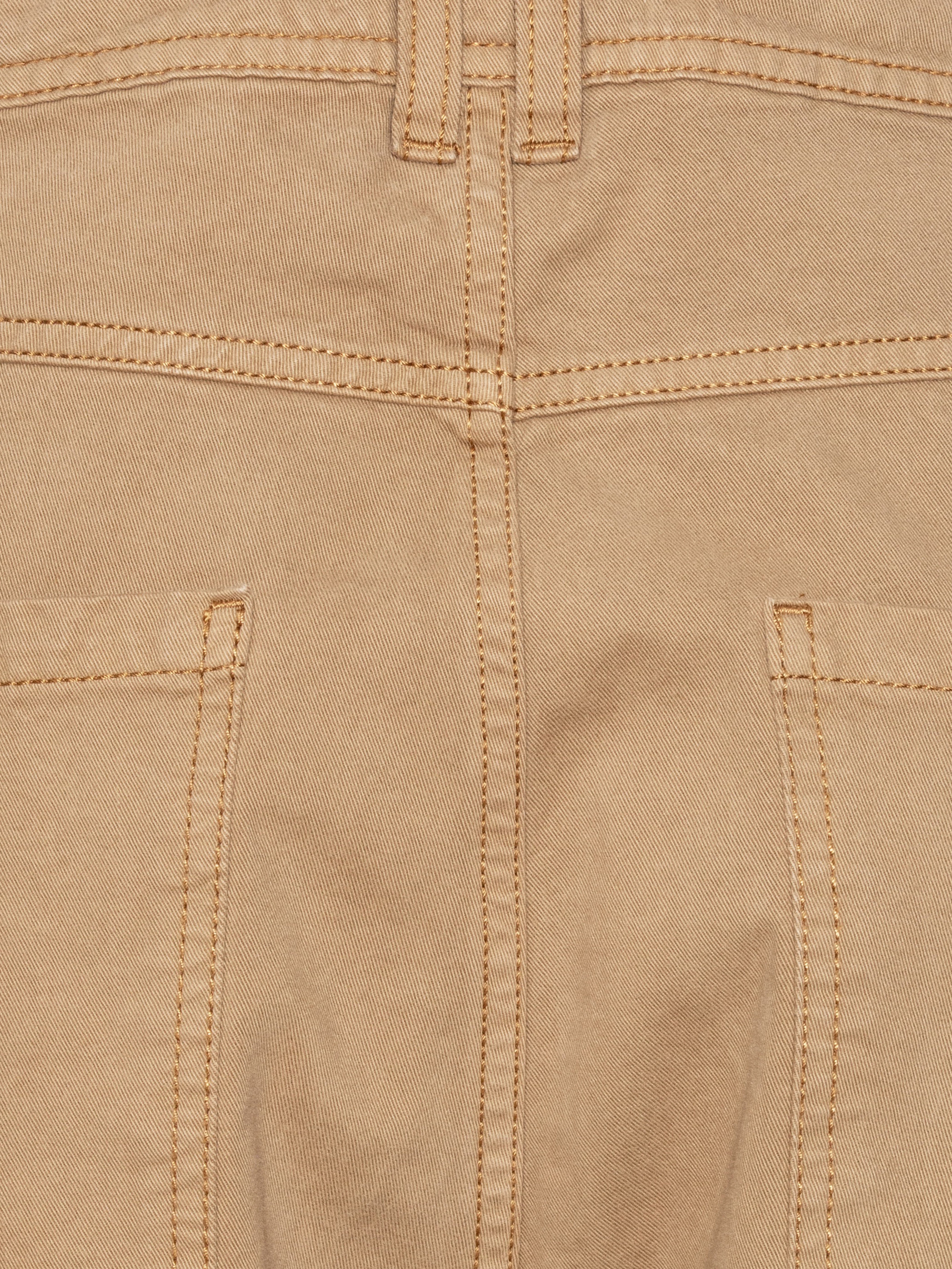Close-up of the Curved Denim Pants showing the dark beige denim texture, waistband with belt loops, and pocket detailing.