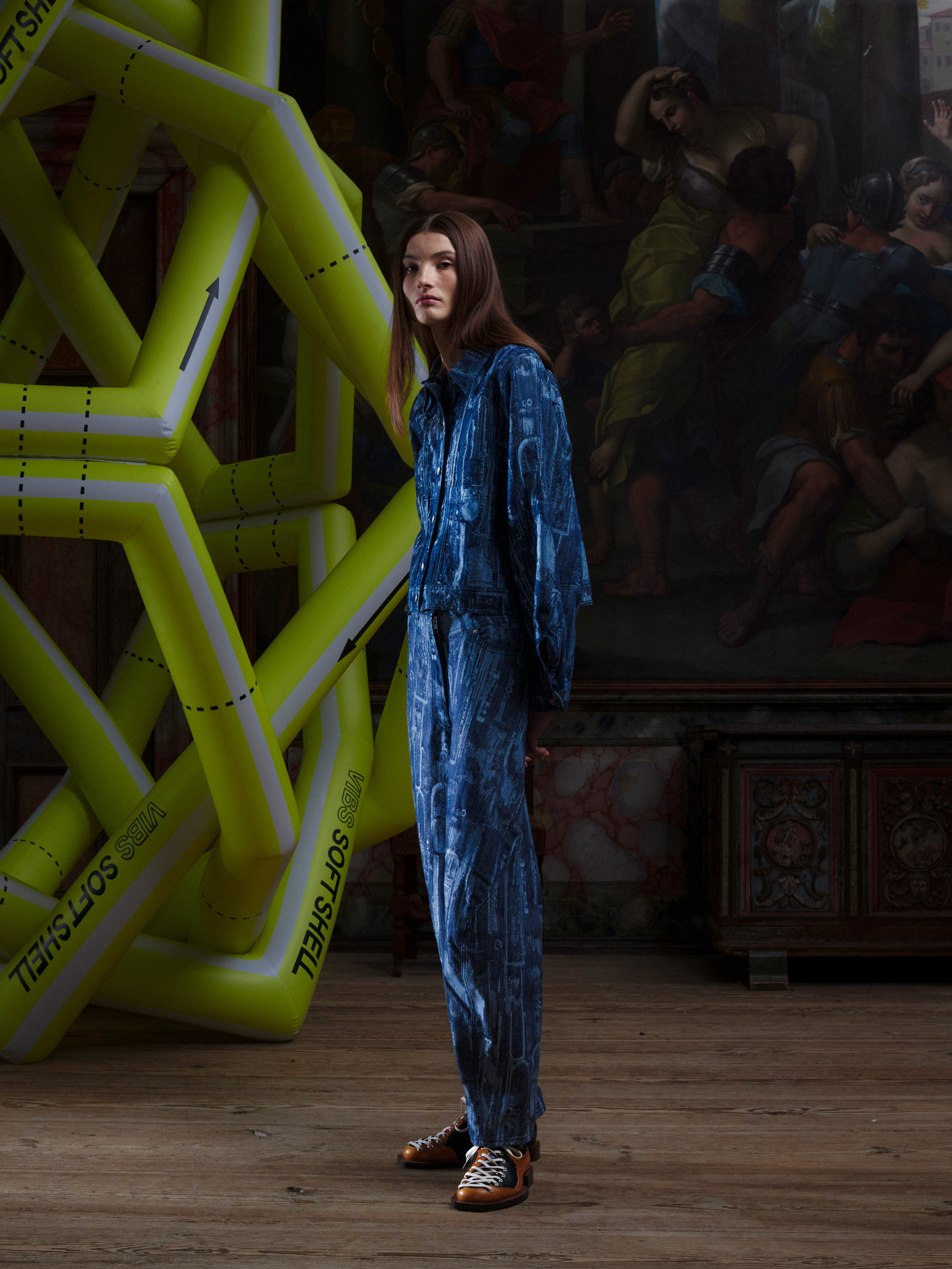 Side view of the female model in the Curved Denim Pants, highlighting the curved leg shape, side pockets, and abstract printed denim. Model is 185cm tall and wears size L.