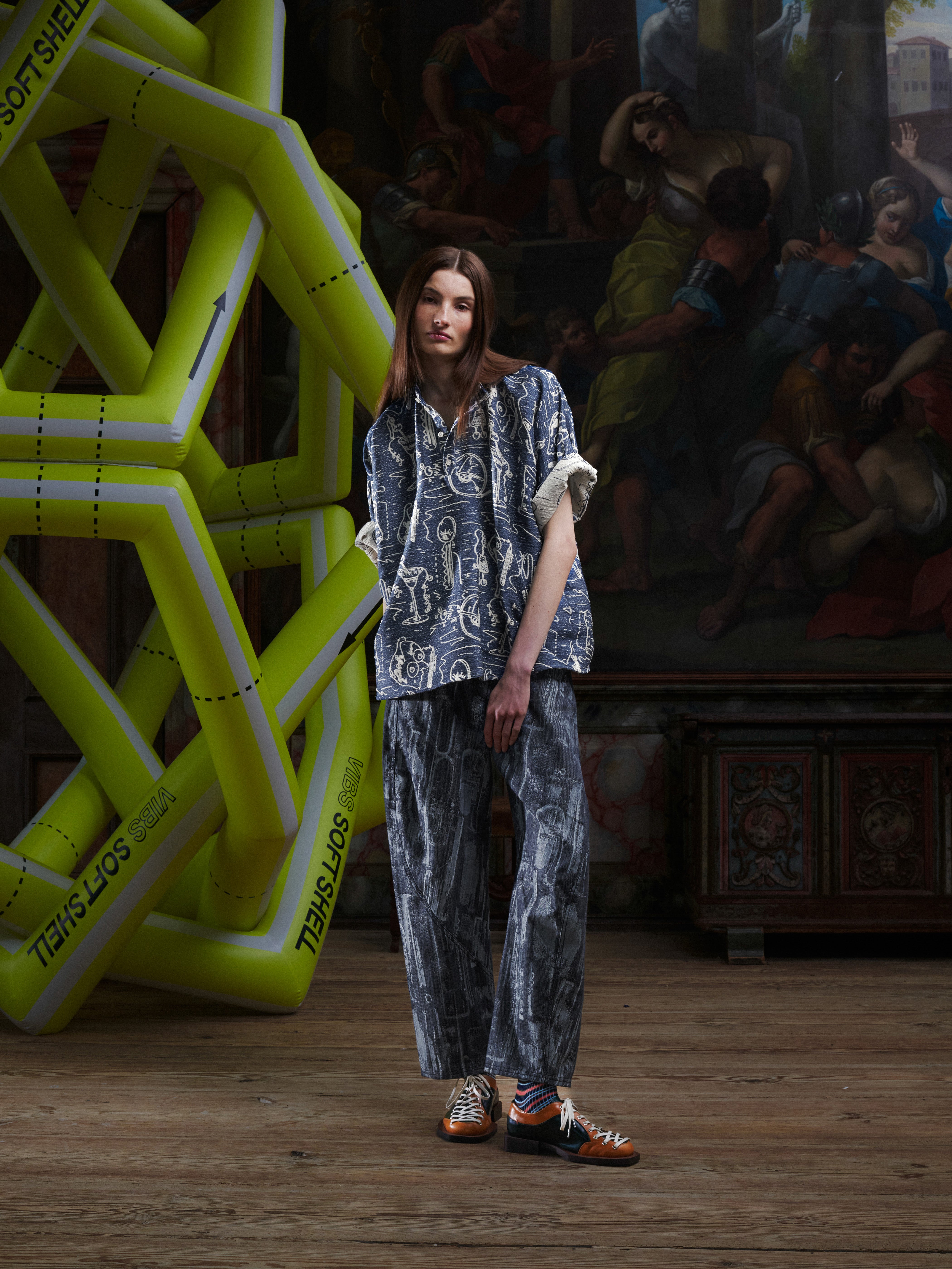 Female model wearing the Dart Polo Shirt from the front, showing the oversized silhouette, mandarin collar, and doodle print. Model is 185cm and wears size L.
