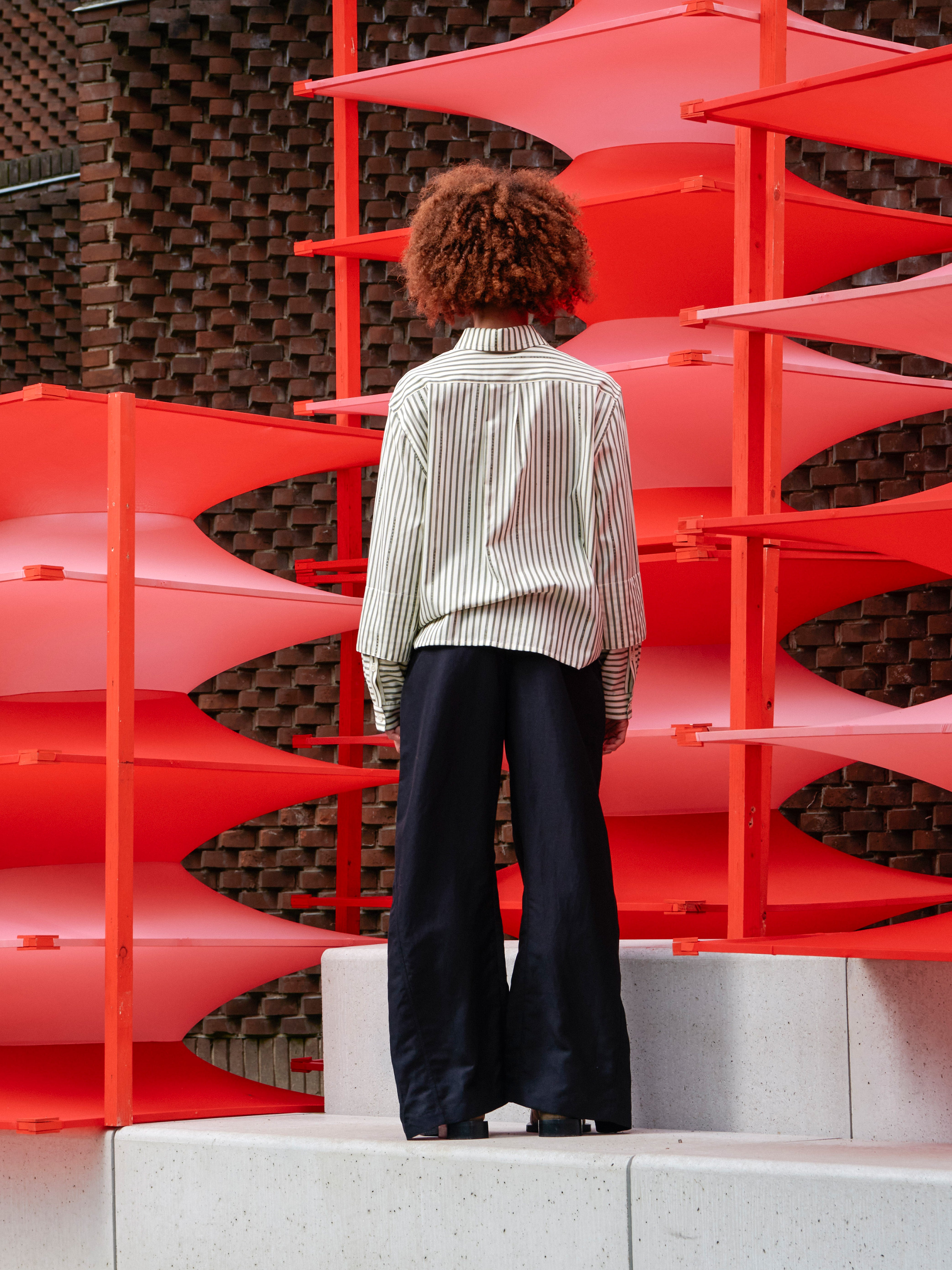 Back view of the model wearing the Merge Pants, showcasing the wide-leg silhouette and structured waistband.