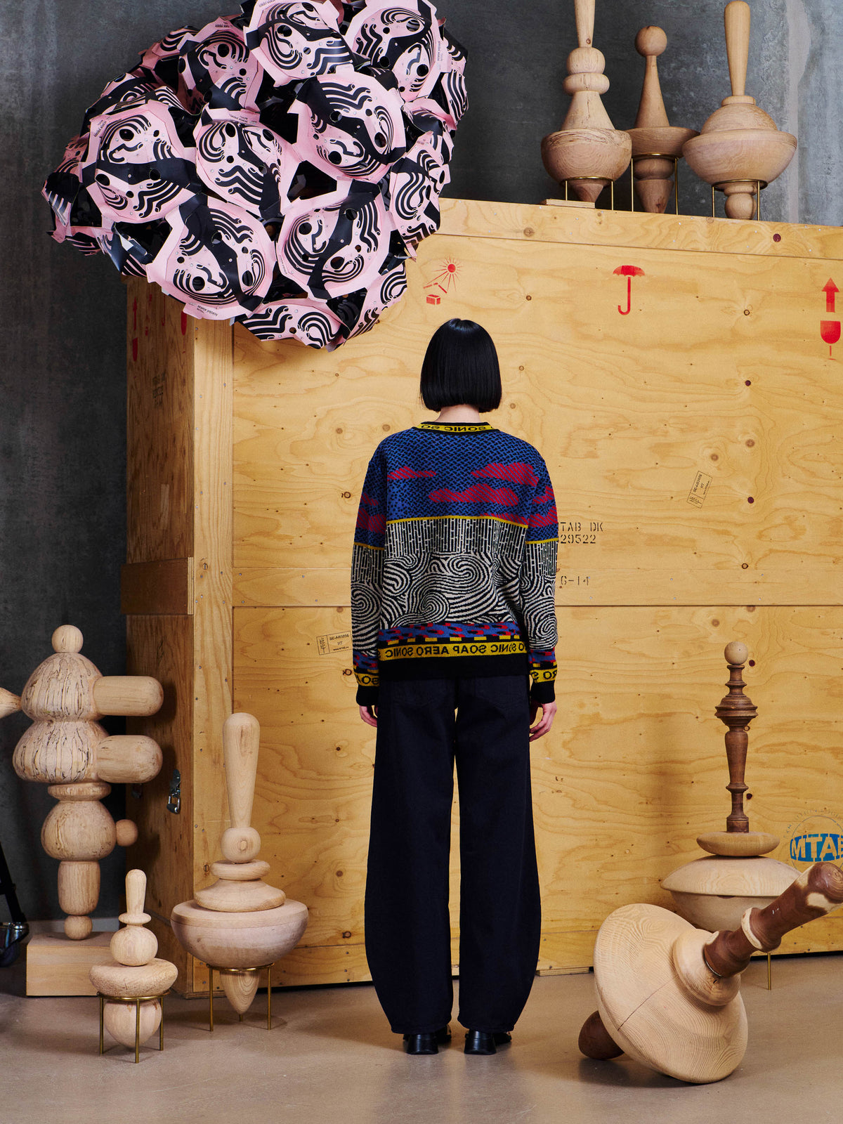 Henrik Vibskov Pipette Pants Anniversary in Black worn back view with a graphic knit sweater, showing the rounded wide-leg shape and back fit.