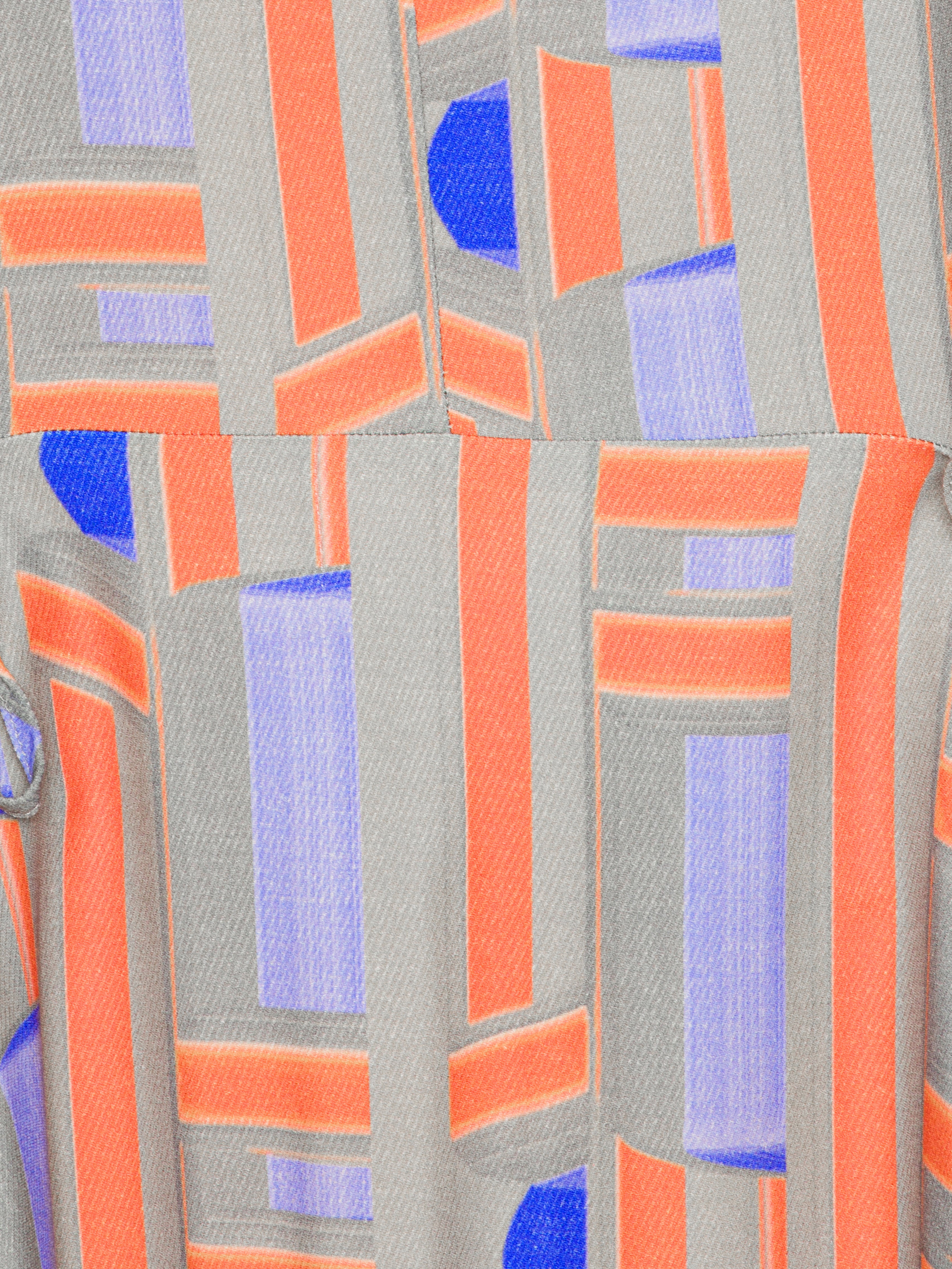 Close-up of a fabric with geometric pattern featuring orange, blue, and gray colors.