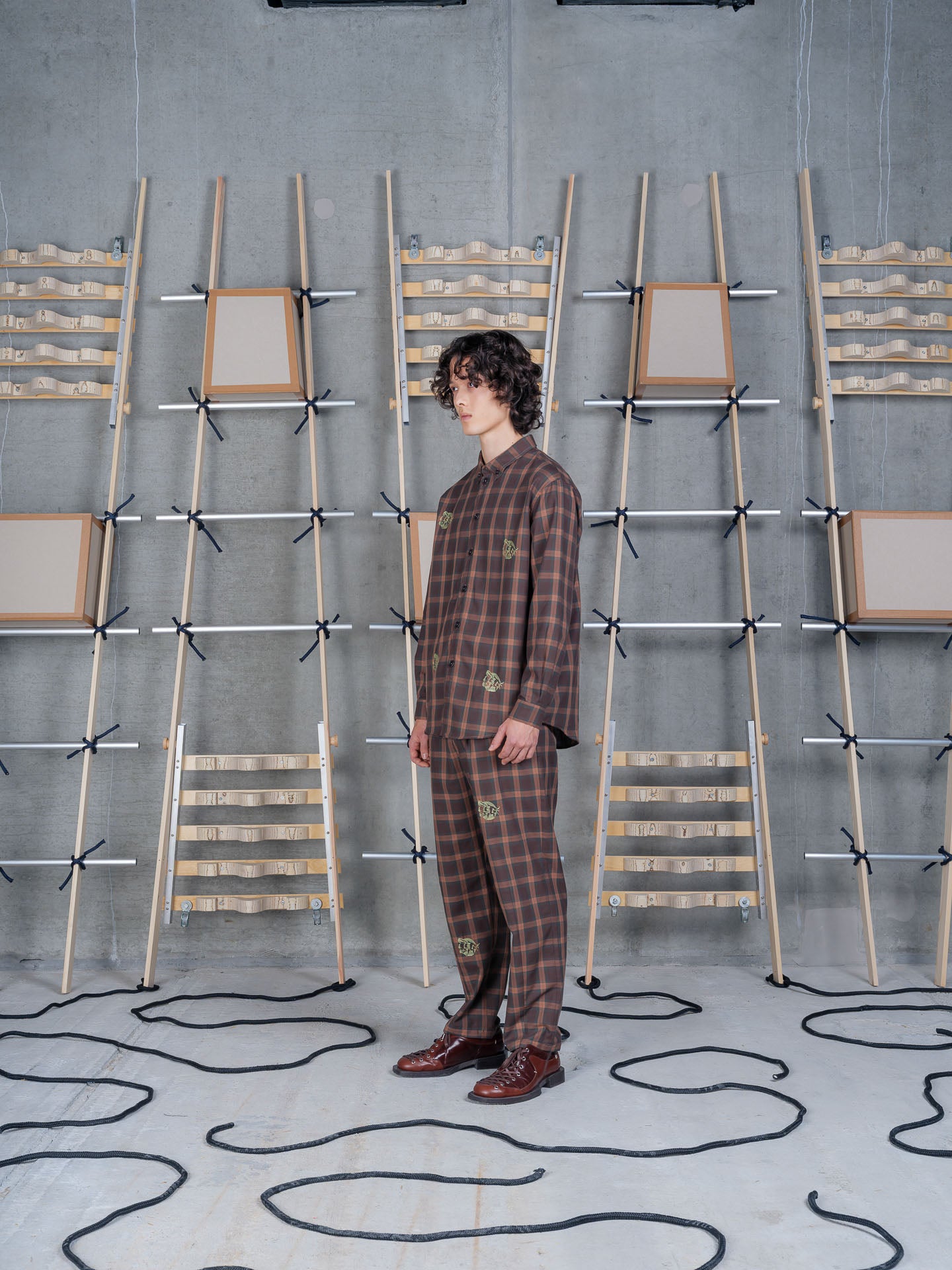Henrik Vibskov Razor Pants Brown Cotton Checks, model side view, showing pleated front and tapered leg