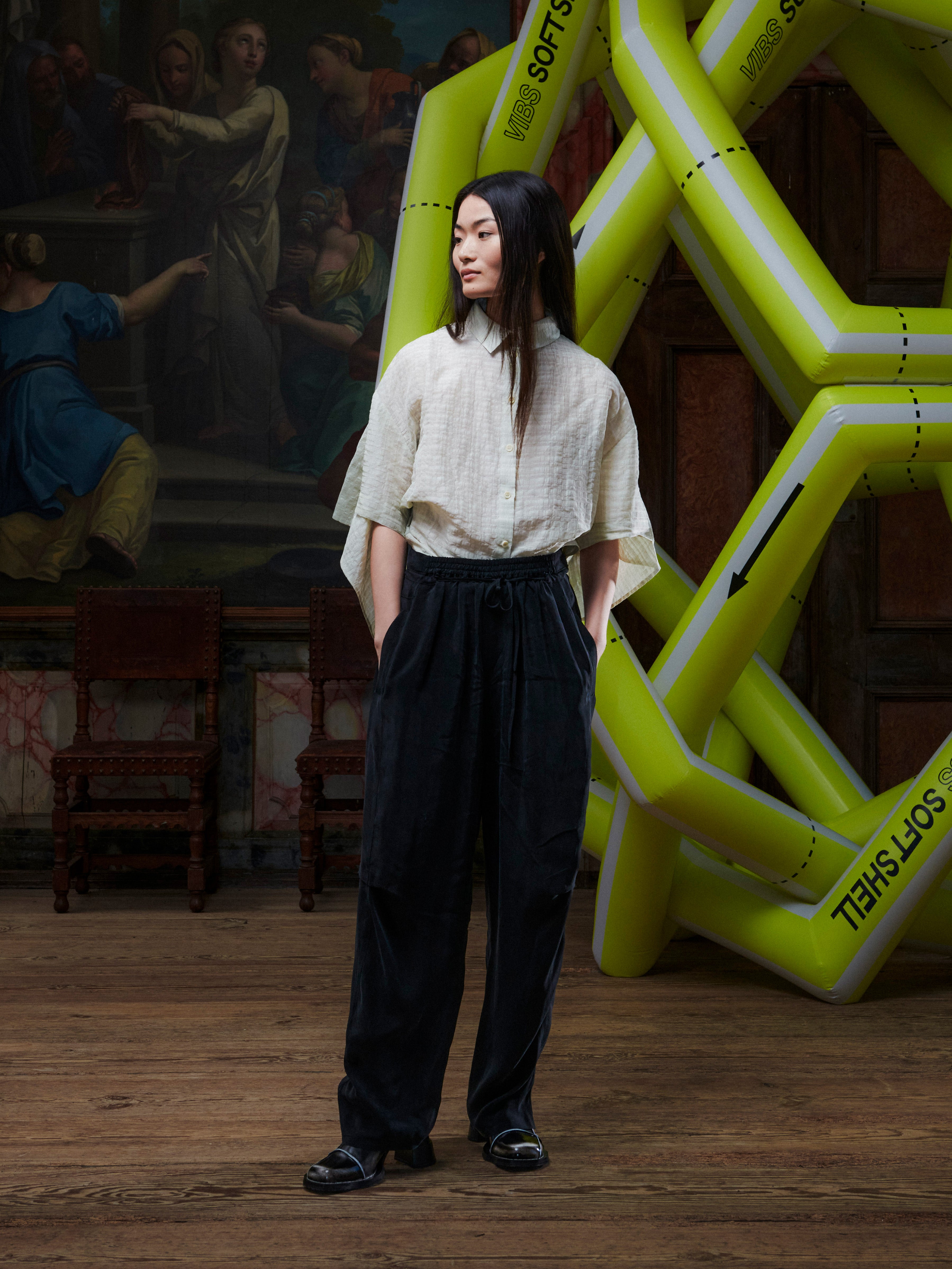 Person wearing a light-colored top and dark pants standing in front of a large inflatable sculpture with text.