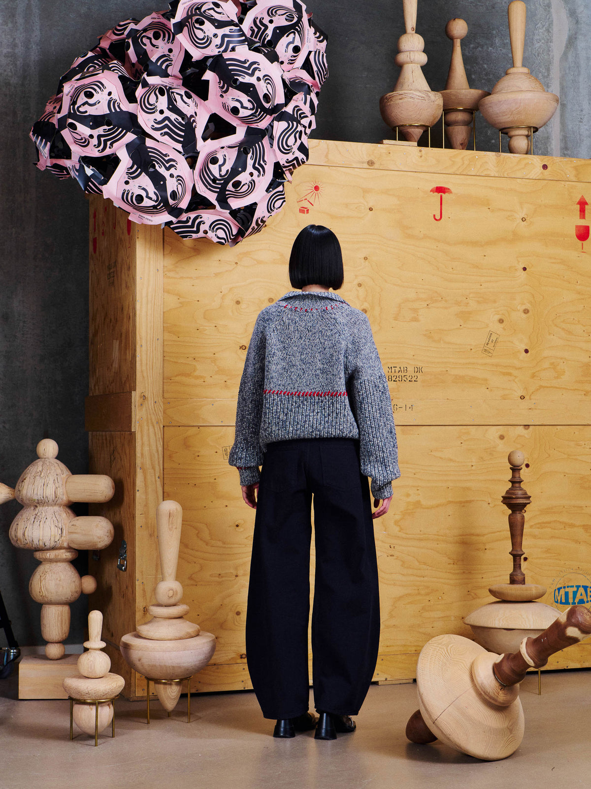 Back view of model wearing the Henrik Vibskov Stitch Cardigan in Red Stitch Grey Melange, showing contrast stitch detailing across the back and collar.