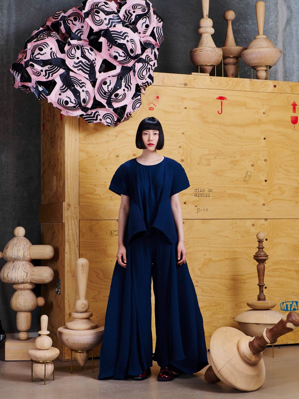 Model wearing the Henrik Vibskov Wrist Plisse Pants in Dress Blue from the front, showing the wide-leg silhouette and long pleated side panels.