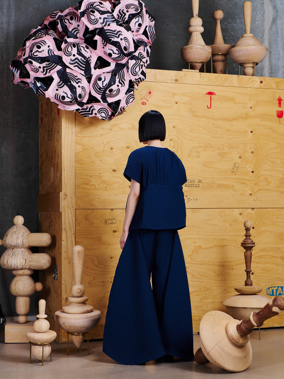 Back view of model wearing the Henrik Vibskov Wrist Plisse Pants in Dress Blue, showing the dramatic wide-leg shape and layered pleated panels.