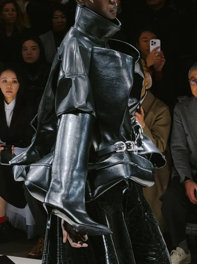 Side runway view of the Junya Watanabe Belted Jacket in Black, highlighting the dimensional front panels, structured sleeves and sculptural silhouette.