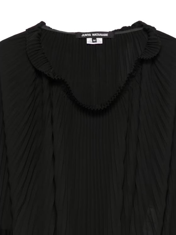 Close-up of Junya Watanabe black blouse showing the pleated neckline and fine pleated front panel.