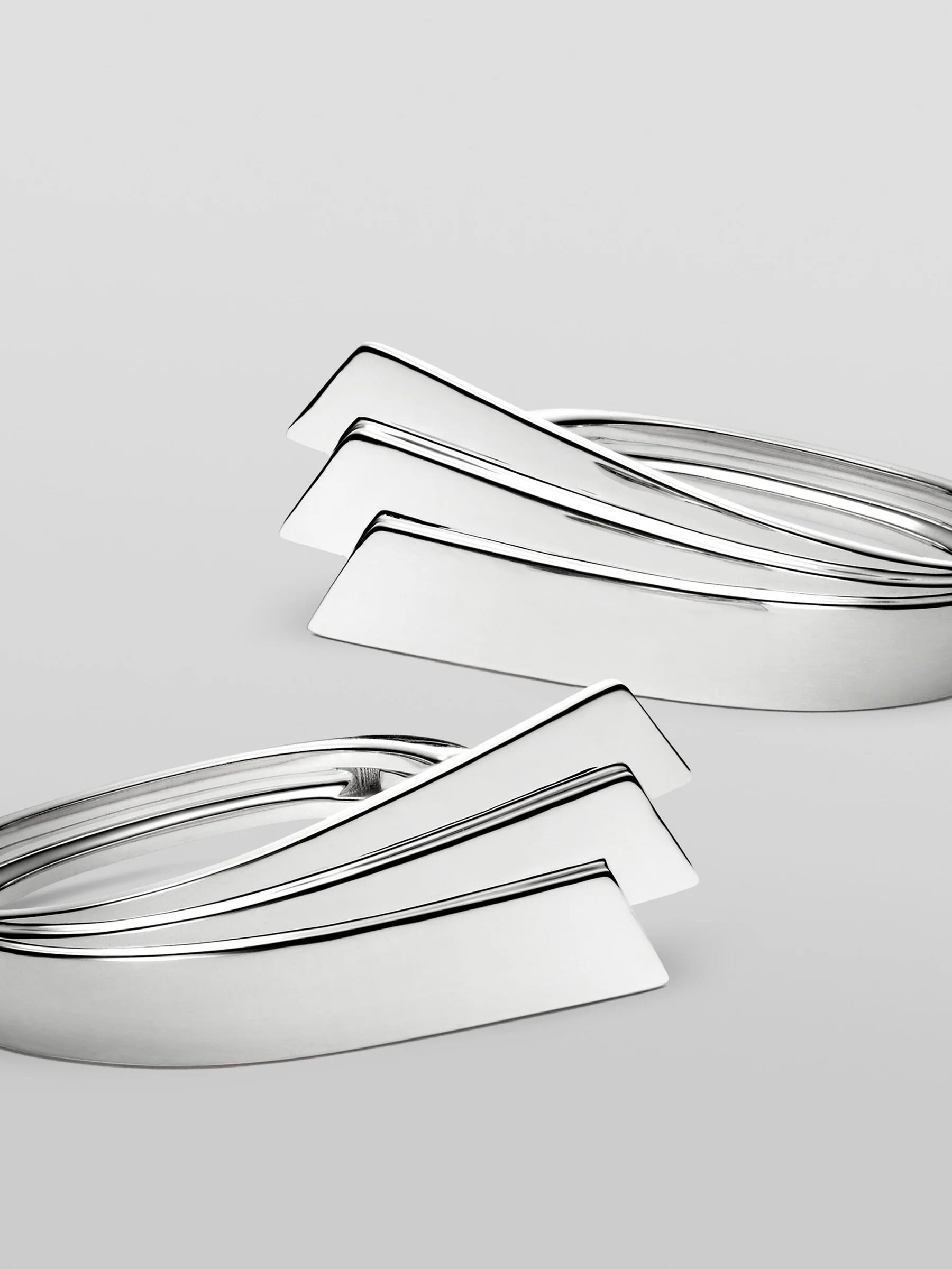 Close-up of Kinraden Symmetry Earring Pair in sterling silver showing folded fan-like silhouette and polished line detailing