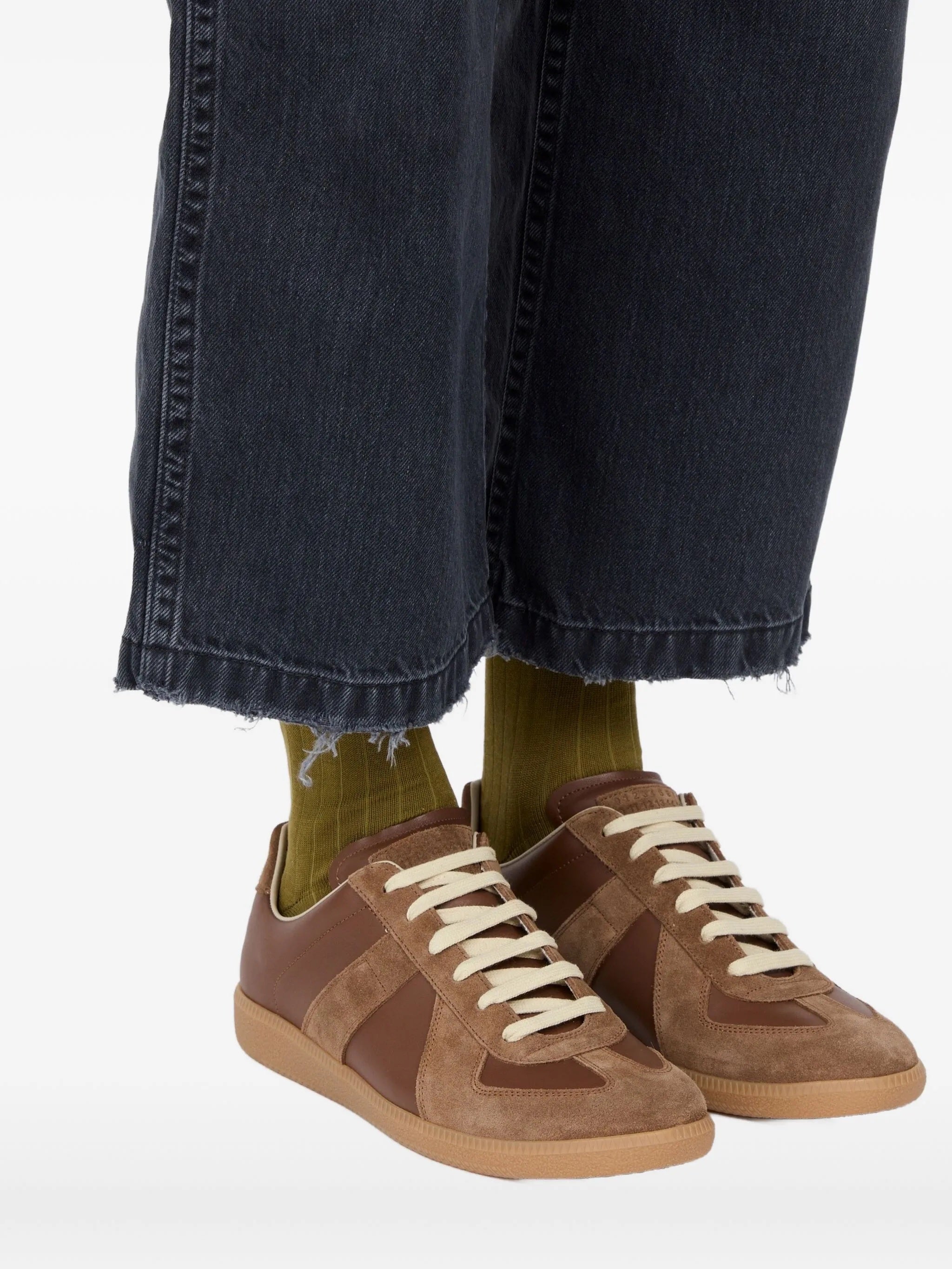Someone wearing the brown leather sneakers from Maison Margiela on a white background