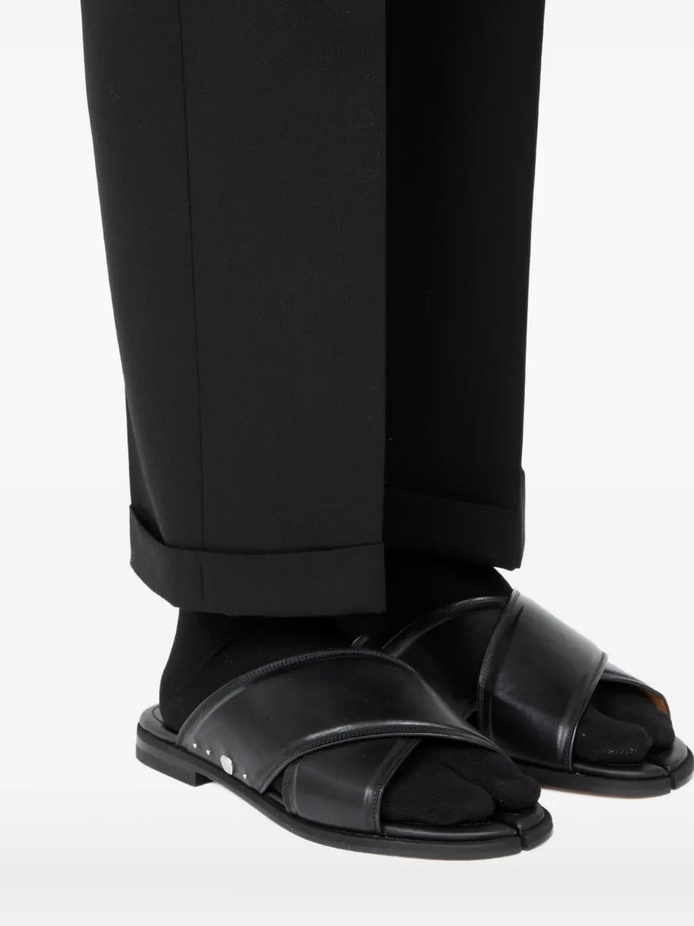 Model wearing the Tabi Numbers Crossed Sandal in Black black calf leather flat sandal with crossover strap and signature split toe, front view – Maison Margiela
