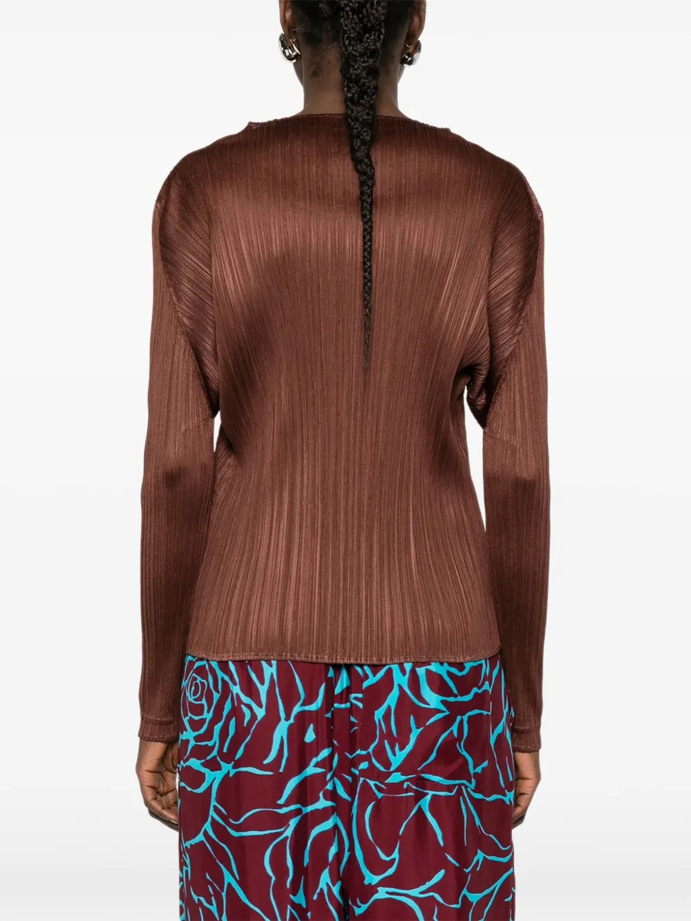 Back view of a model wearing the brown, long sleeve, pleated top by Pleats Please Issey Miyake on a white background