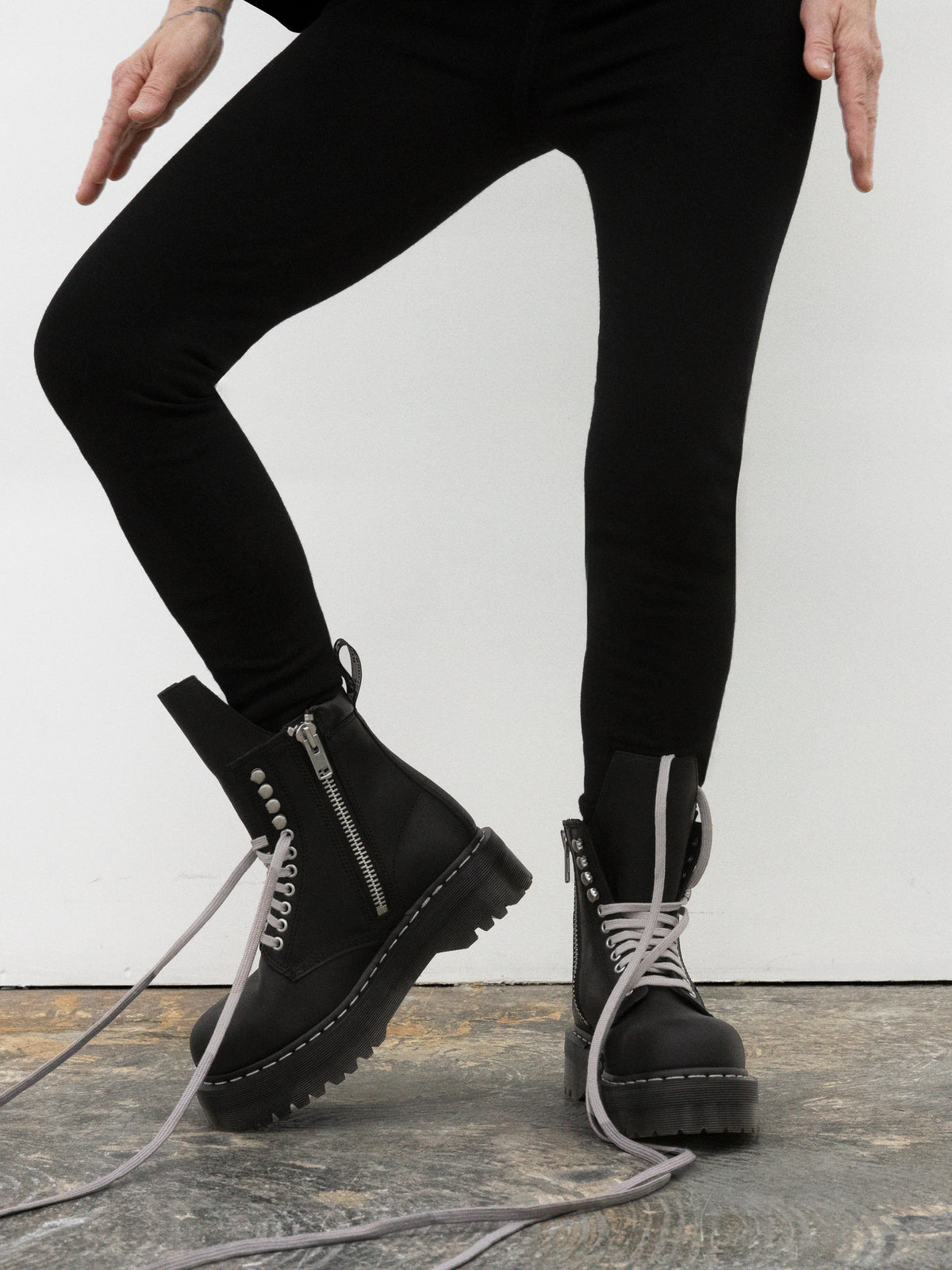 Rick Owens x Dr. Martens FW26 black lace-up boots worn on foot with oversized grey laces and rugged platform sole.